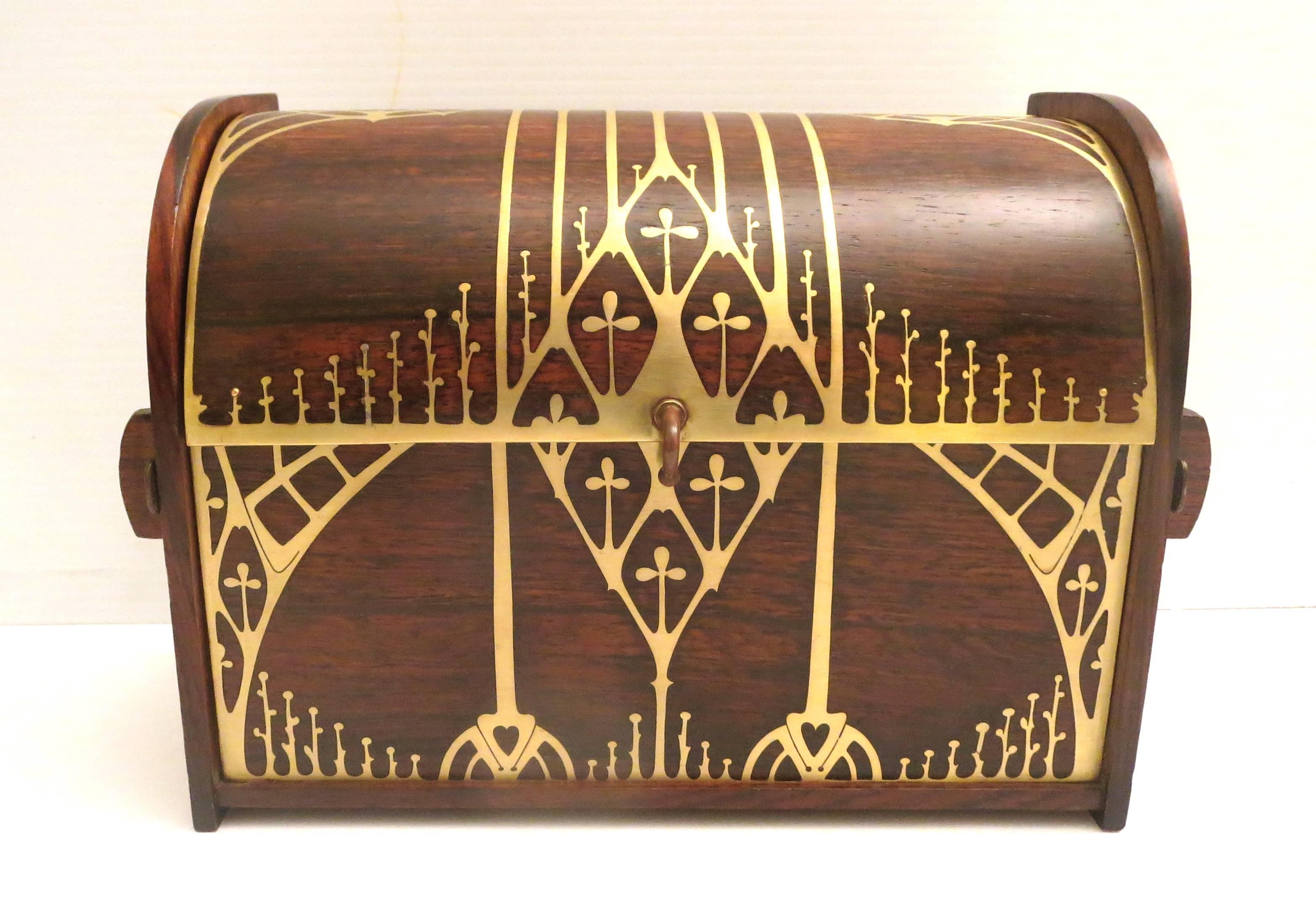 An Art Nouveau writing box crafted with palisander (rosewood) and brass decoration. Domed lid on a high quality, hinge opens to reveal two compartments separated by a brass removable divider, with silk top inlaid and copper decorations on the side a