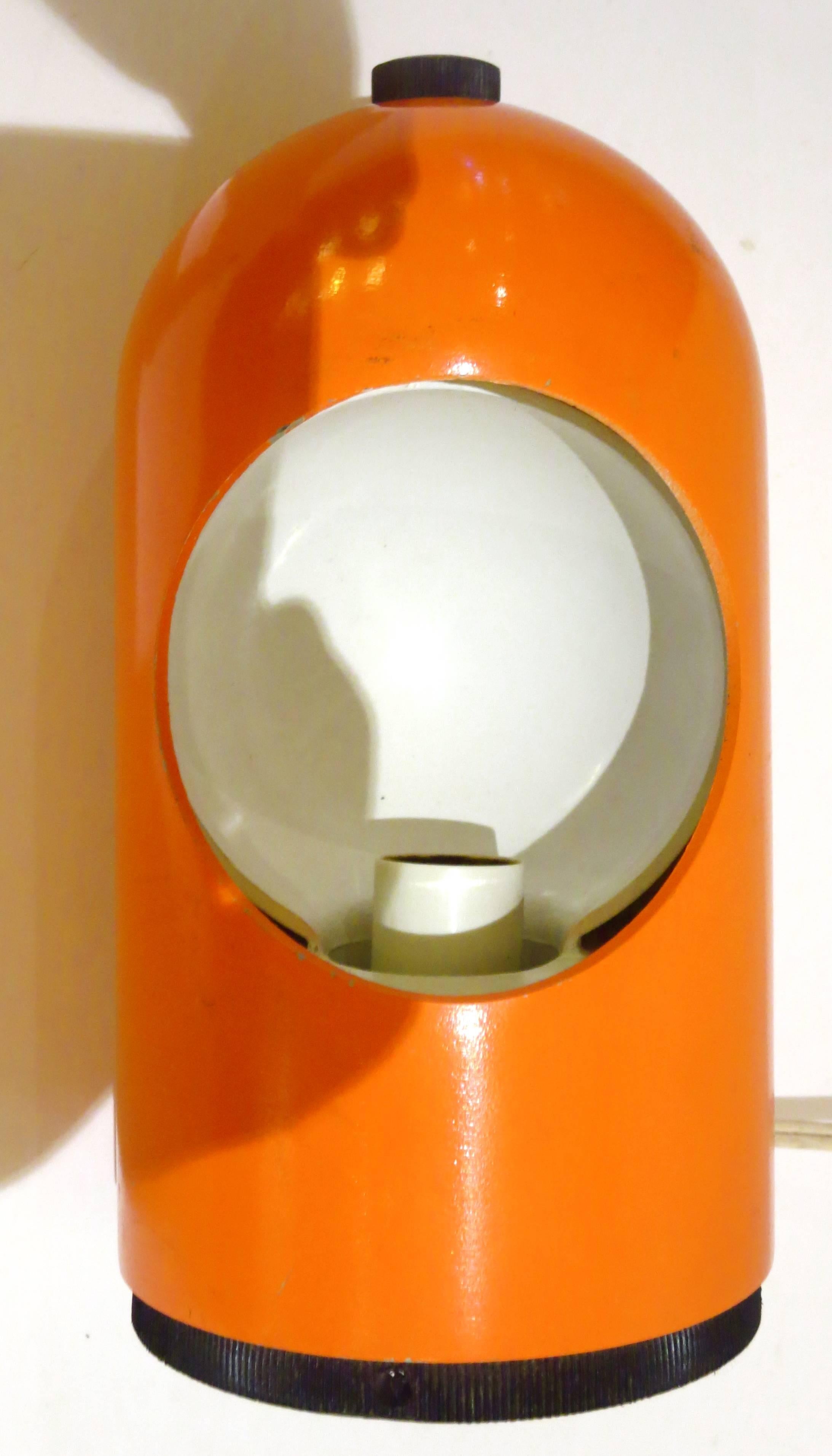 Orange eclipse lamp was manufactured in the United States by Lightolier during the 1960s. Designed by Joe Colombo an orange lacquered metal exterior with a white inside and a rotating screen in the center and plastic base with original label.