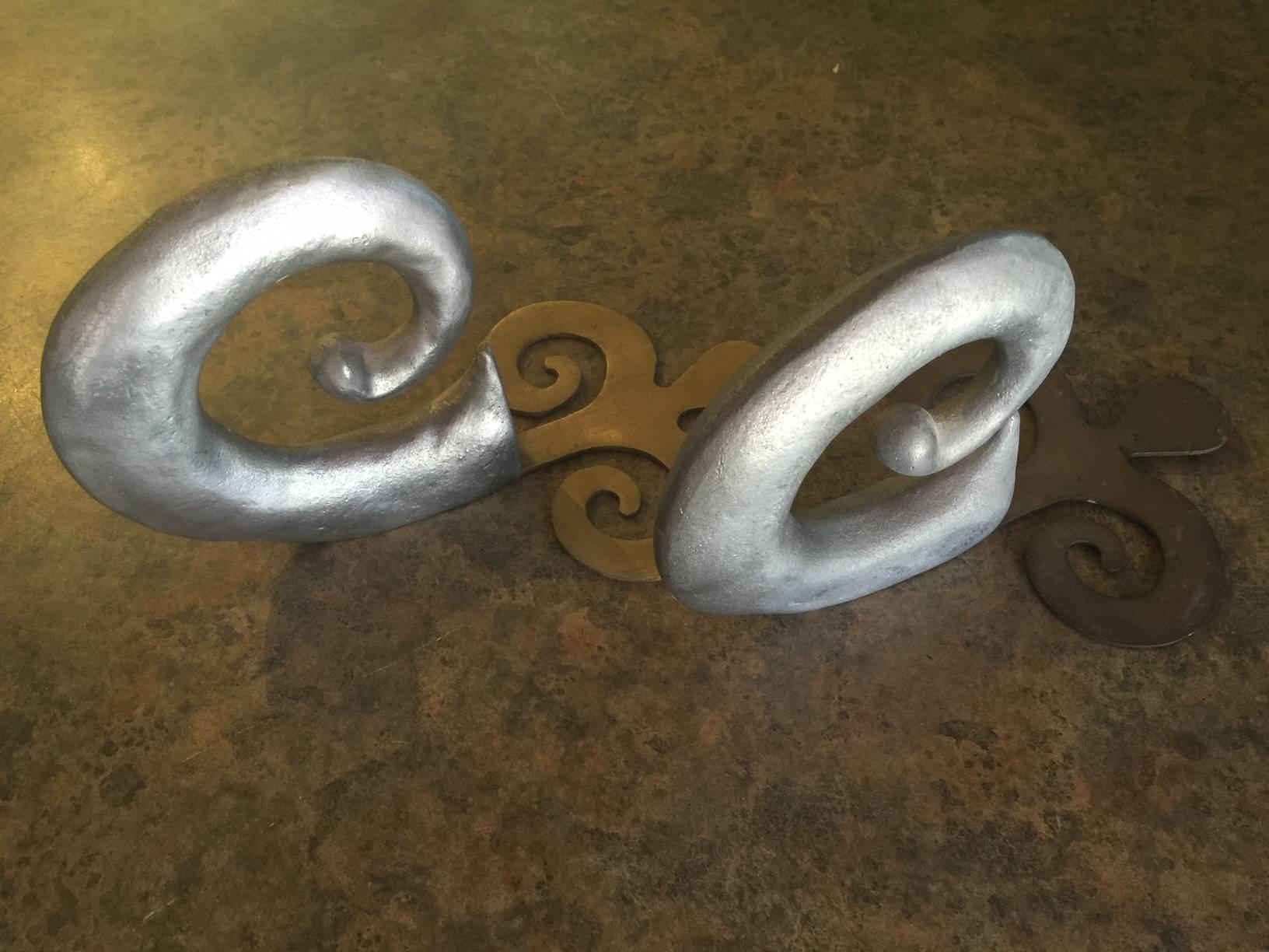 An early pair of heavy cast aluminum swirl bookends signed 