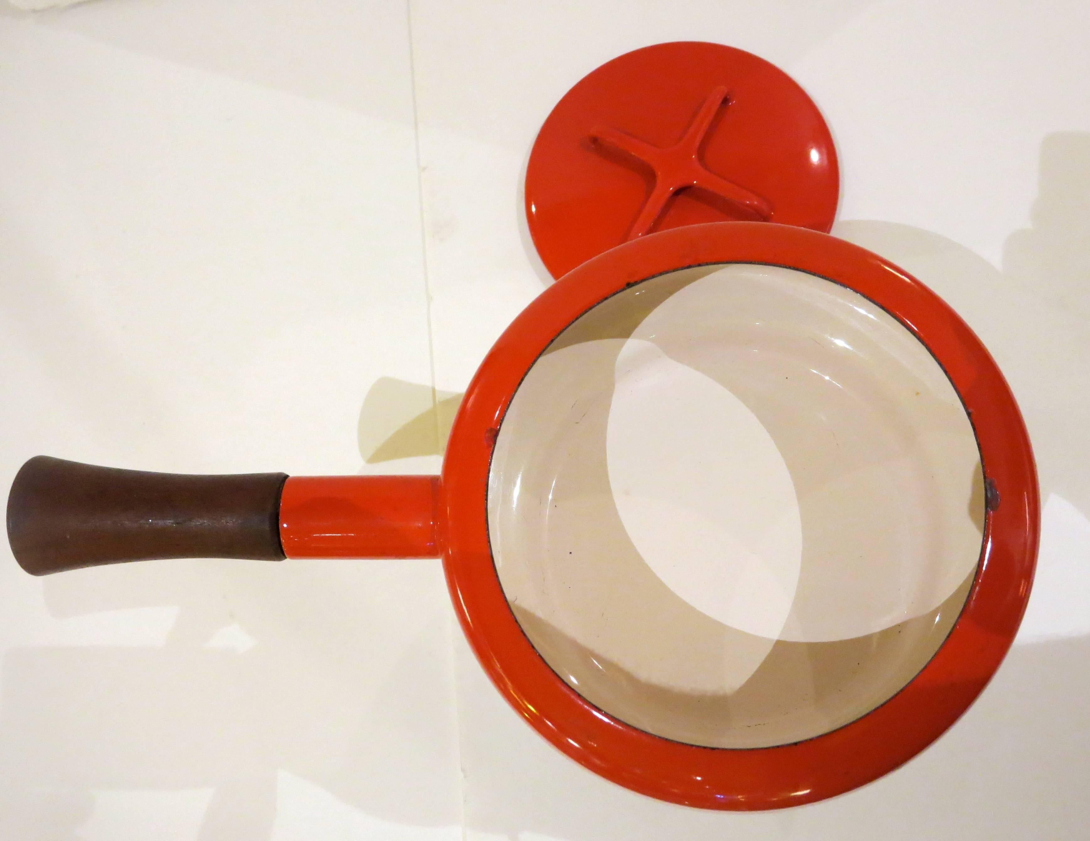 Beautiful, unique, very nice and clean, 1950s fondue pot, in red enameled finish with white interior, cast iron base and solid teak handle. Excellent condition. A couple of flea bites around the interior edge as shown, designed by Quistgaard and