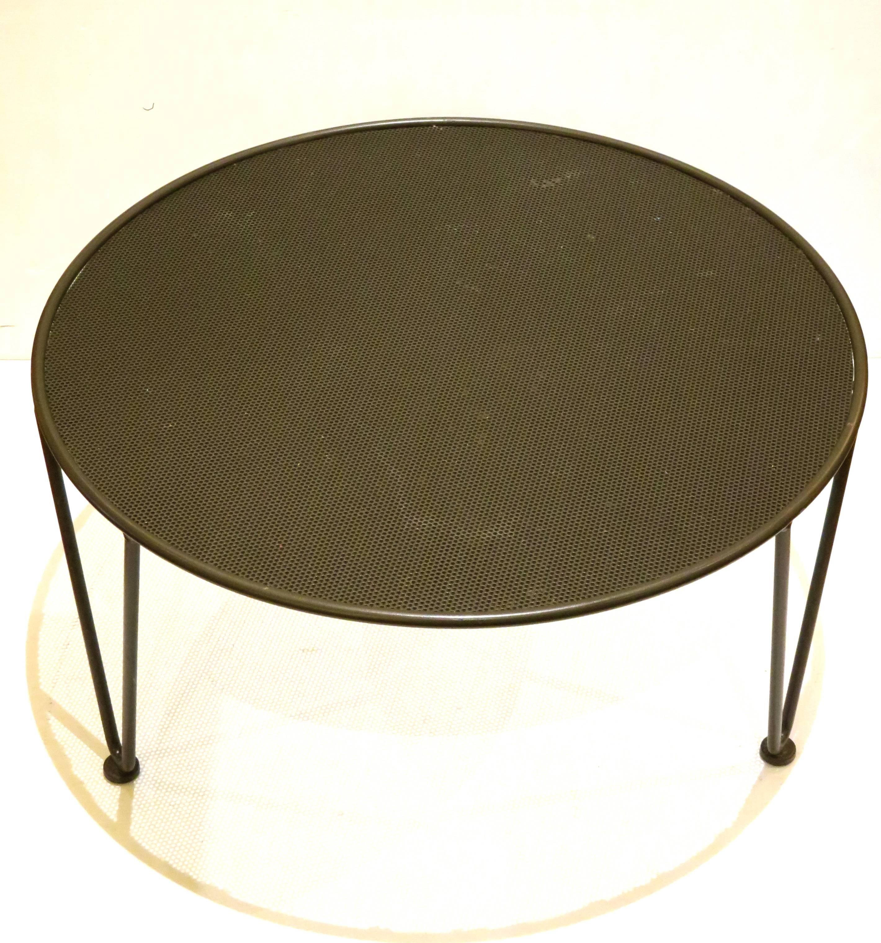 Retro modern iron round coffee cocktail patio table with hairpin legs and perforated top the table has been sandblasted and powder coated in a charcoal finish, the three hairpin legs have plastic bottom to protect the floor.
