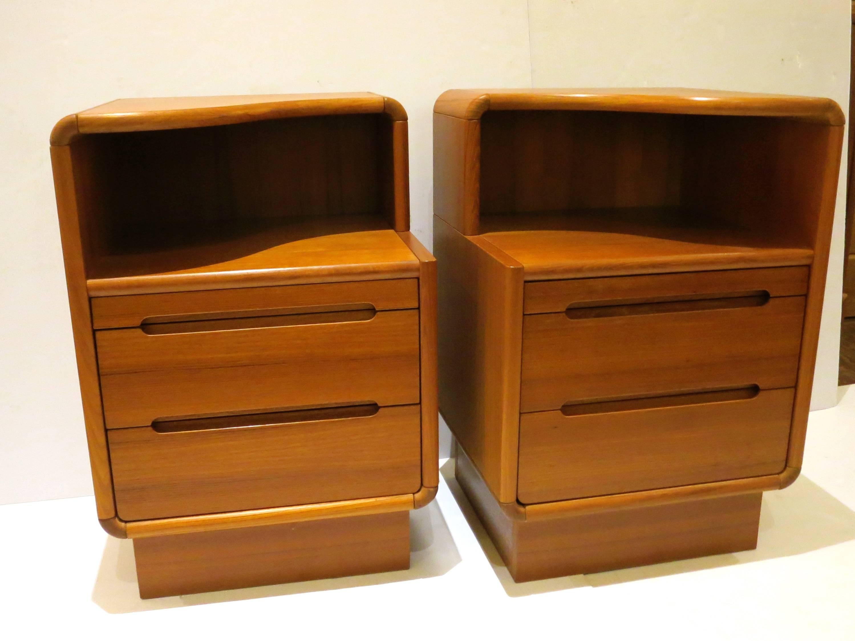 Nice pair of teak nightstands, the solid edging and rounded solid teak corners, two drawers and a pull writing table, nice metal gliders, circa 1980s great condition, refinished in the back, nice organic top.