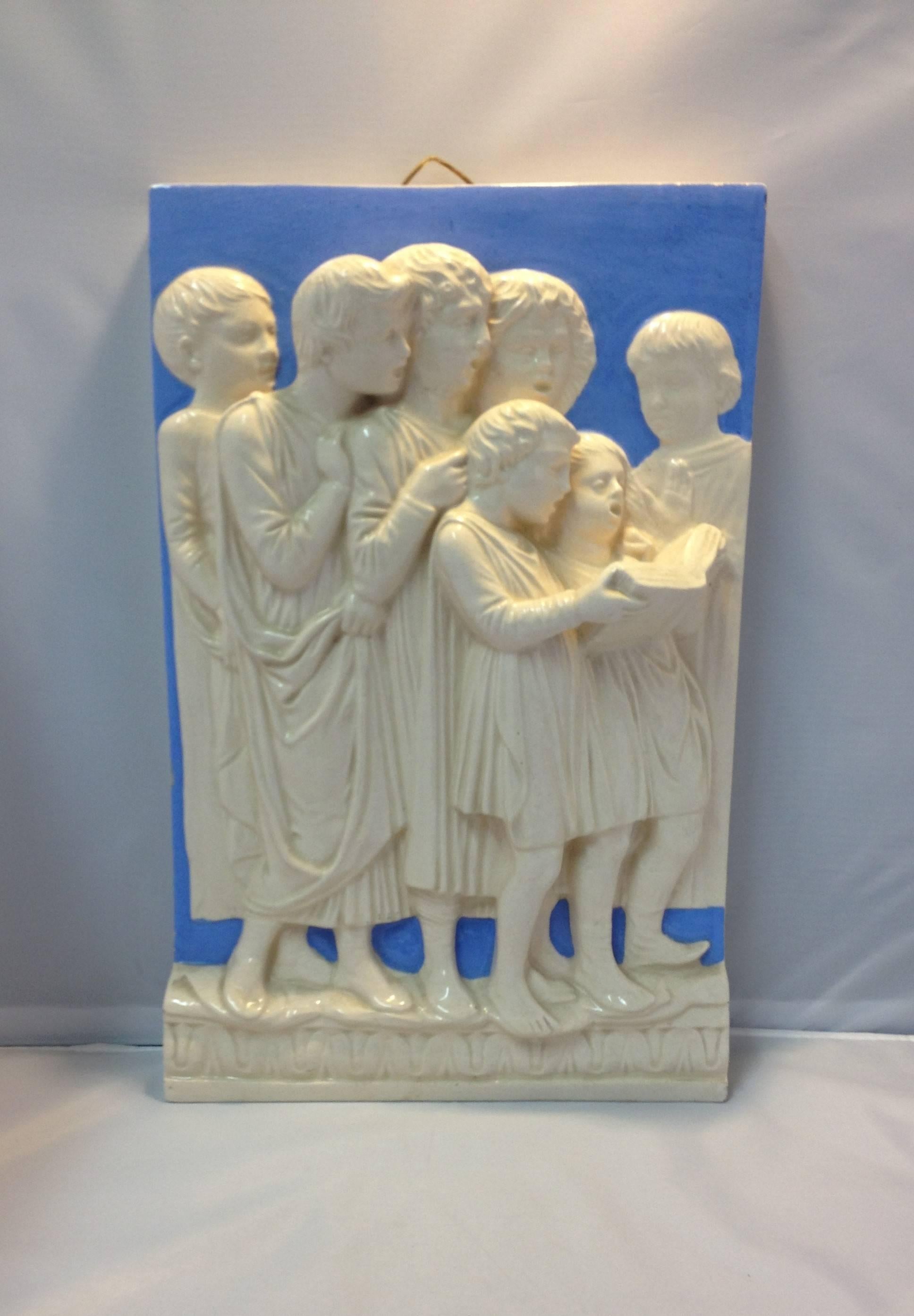 Rectangular high relief Della Robbia polychrome glazed pottery plaque from Italy. The neoclassical work depicts a group of choir boys singing from a hymnal in a Classic Della Robbia blue and white glaze, circa early 20th century.
    