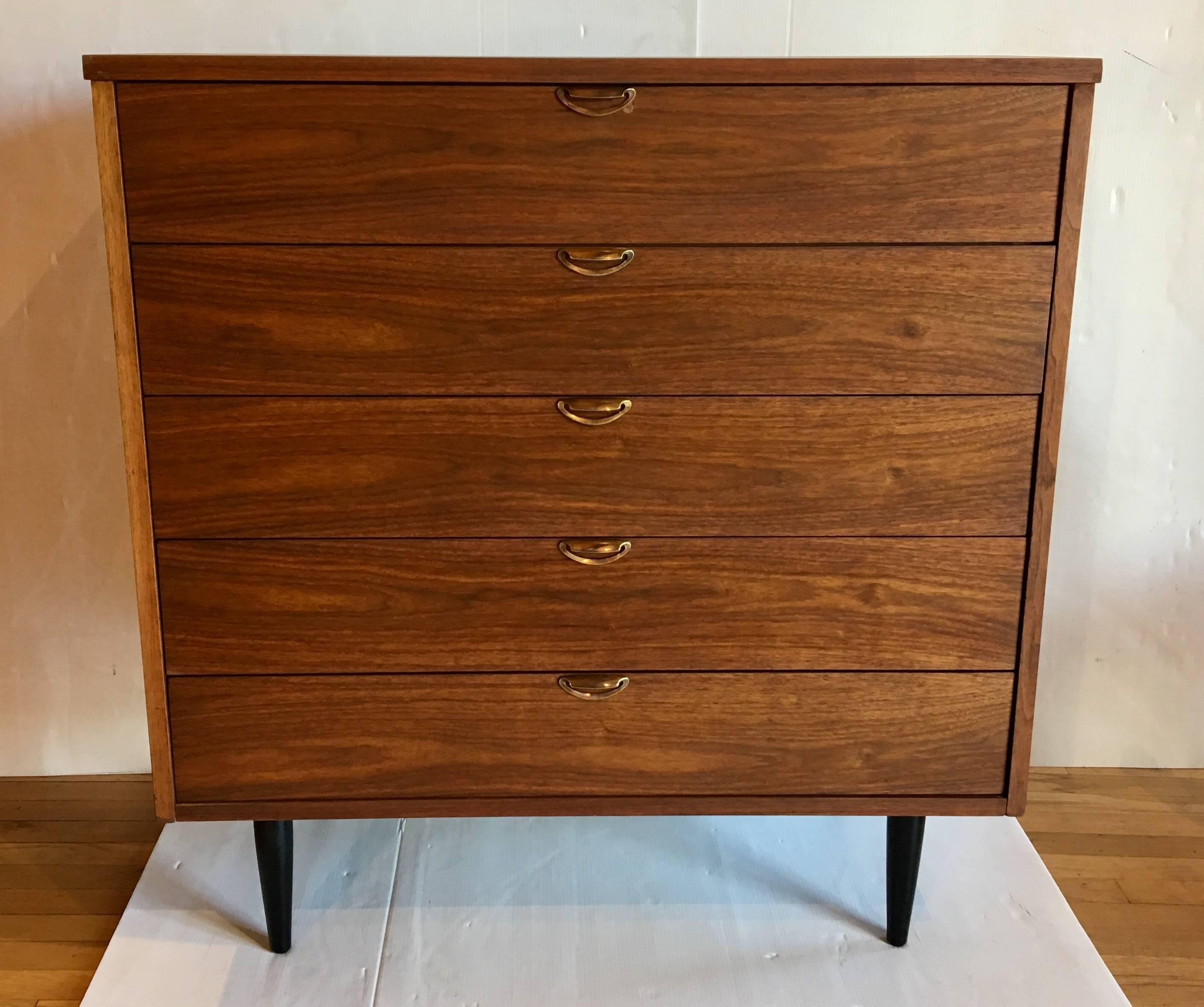 Beautiful freshly refinished 1950s American walnut tallboy chest of drawers, five-drawer with polished solid brass pulls and black lacquered tapered legs, nice dovetail drawers and clean condition.