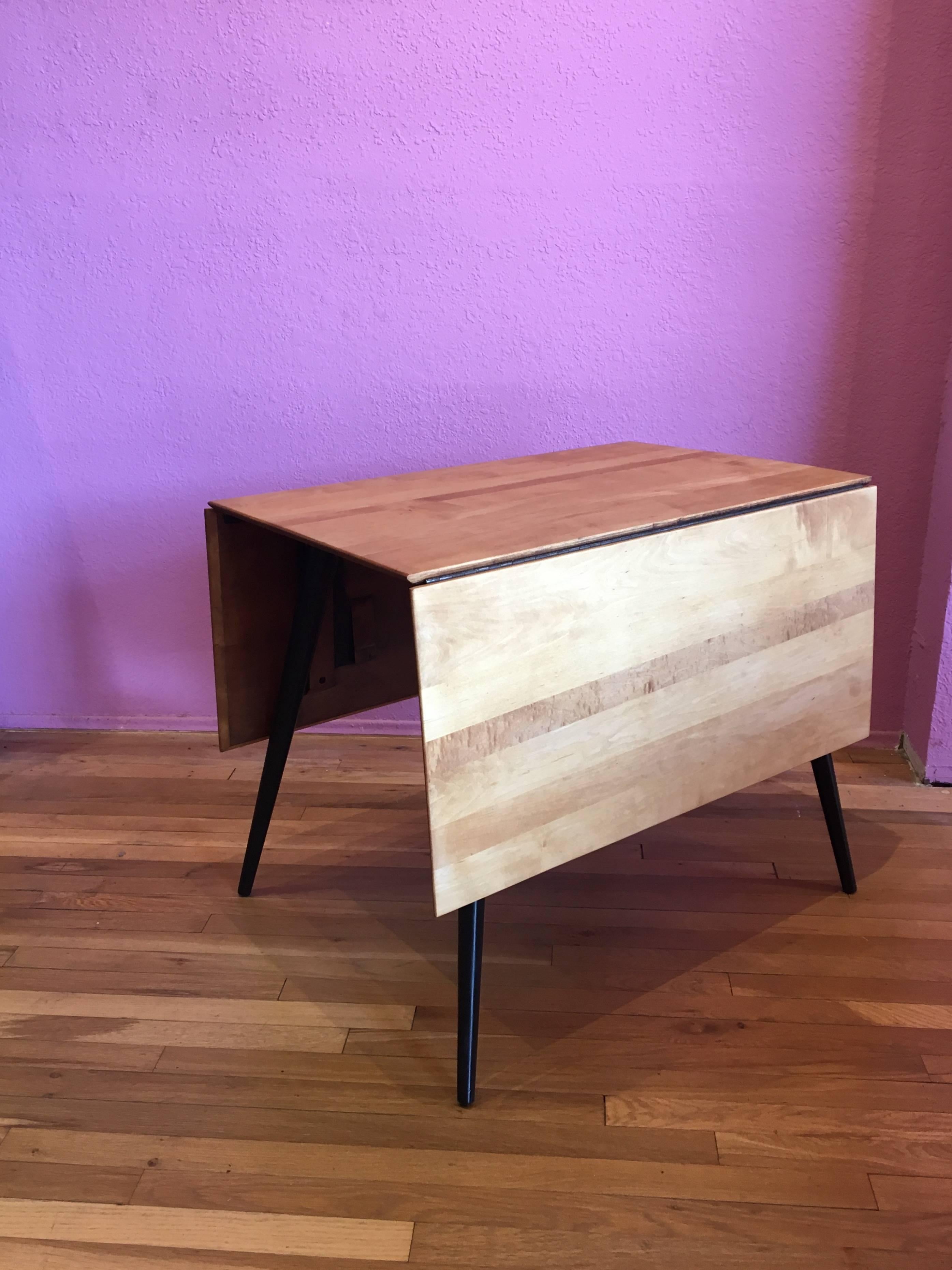 Great design on this versatile drop-leaf dining table designed by Paul McCobb as part of the Planner Group Line, circa 1950s. Freshly refinished, the top is solid wood and the legs have been lacquered in black. The table its solid and sturdy, you