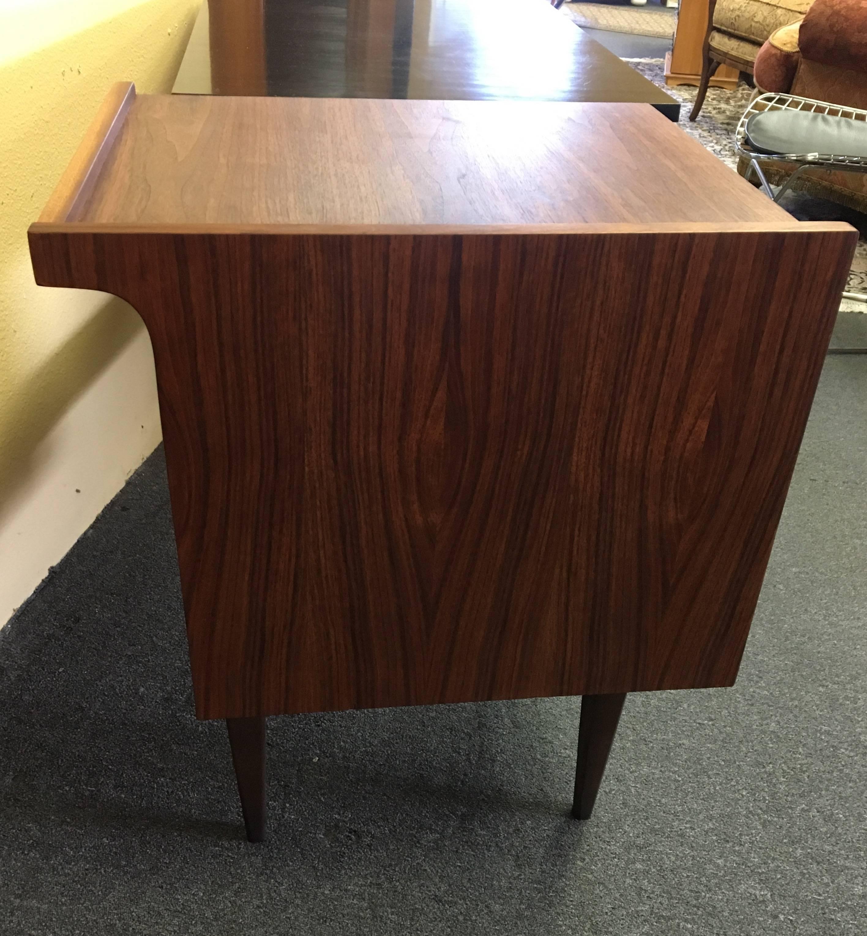 Versatile double sided desk by Hooker, circa 1950s. The desk has a black laminated top with three drawers (one being a large file drawer) and back side with low bookshelf and black enameled handles. The piece is from the "Mainline"