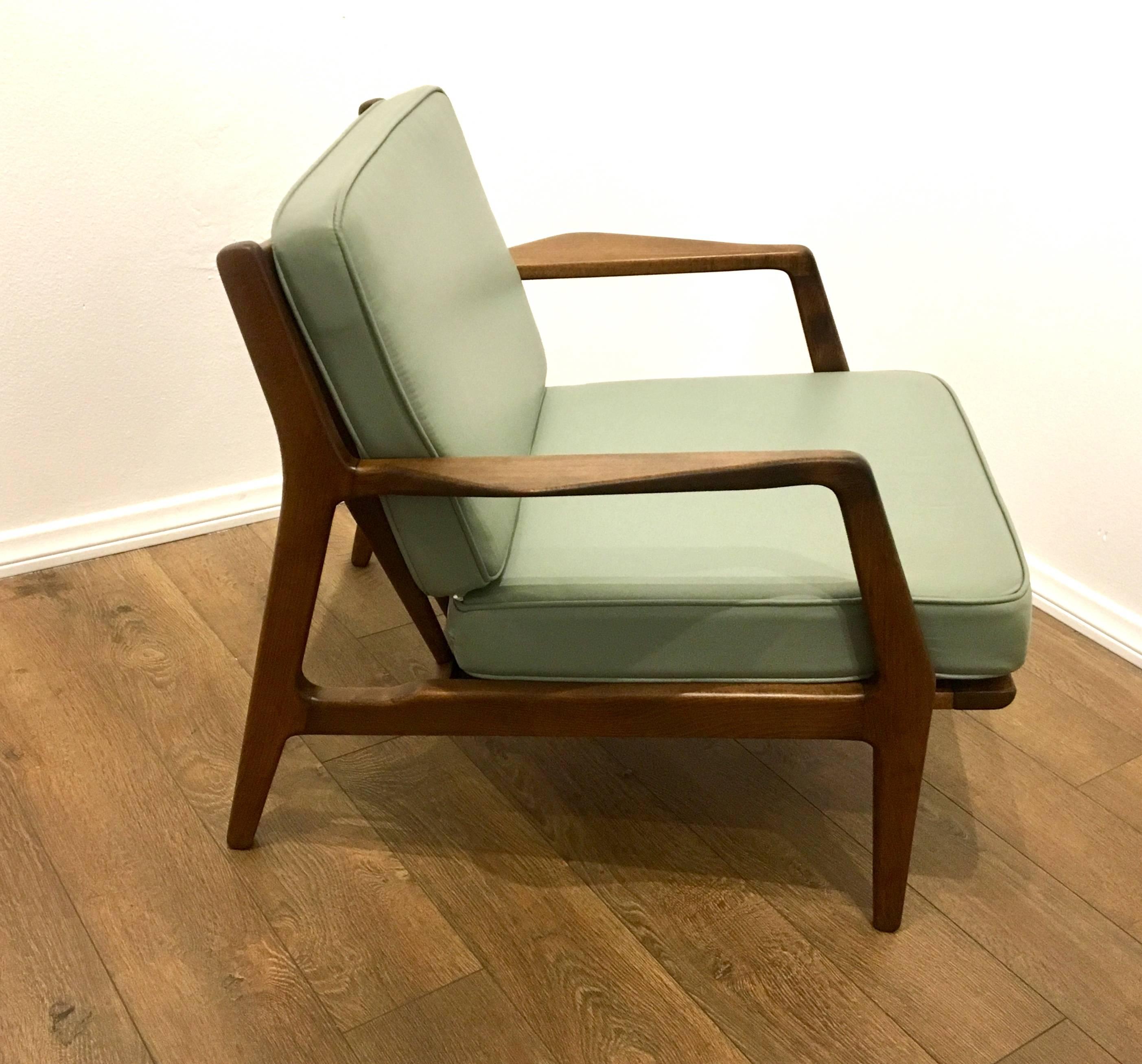 Nice lines on this great lounge armchair designed by Kofod Larsen, circa 1950s freshly recover in sea foam Naugahyde cushions. Solid and sturdy in its original walnut finish.