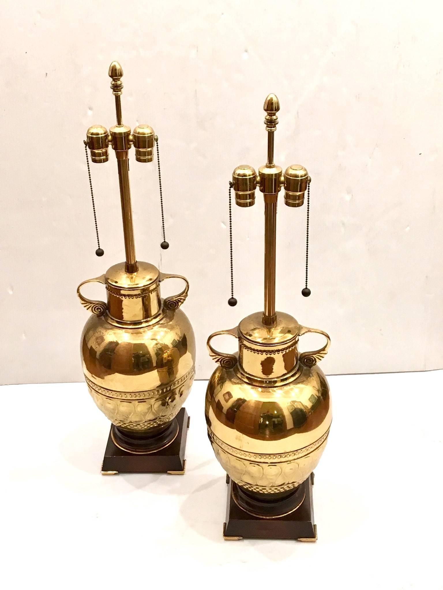 Beautiful and elegant pair of table lamps by Marbro Lamp Company, circa 1960s. All original condition lamp shades not included, double head sockets, patinated brass urns sitting on a mahogany finish lacquered base. Measures: 33 1/2