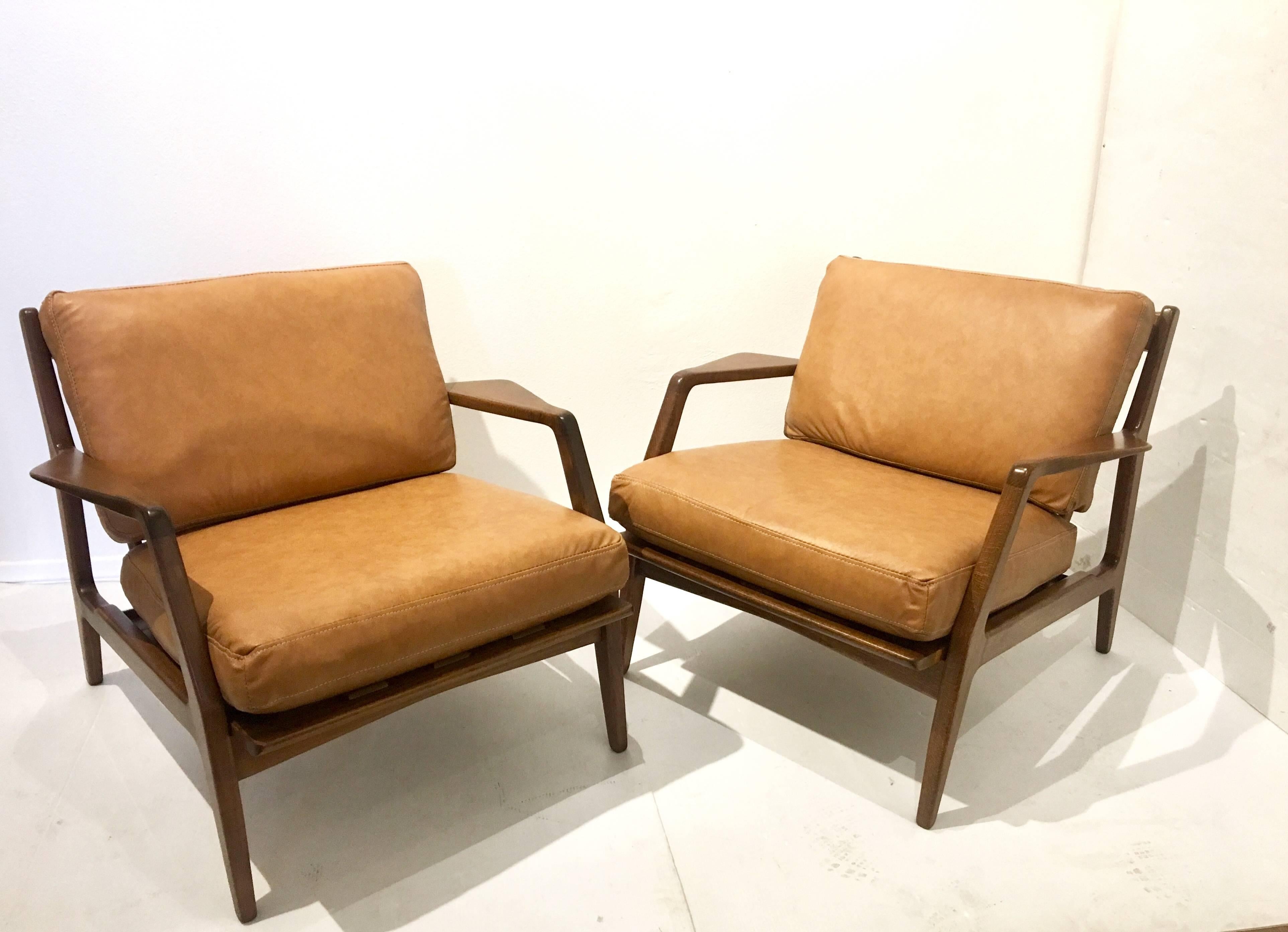Elegant pair of lounge chairs by Kofod Larsen in camel color leather, freshly recovered and refinished in a walnut stain, solid and sturdy made in Denmark, circa 1950s.