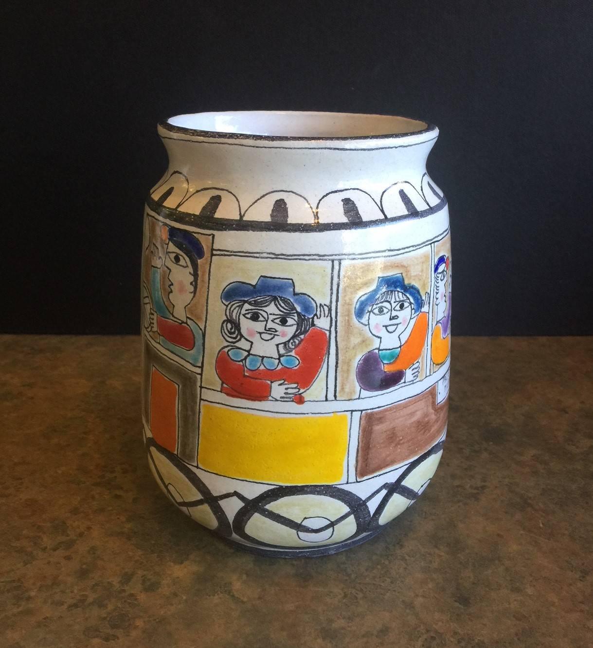 A wonderful and colorful Giovanni de Simone hand-painted pottery vase, circa 1960s. from Italy. The painting depicts a number of passengers on board a moving train with several birds trailing in flight. The vase is 7.75" high and 5/75" in