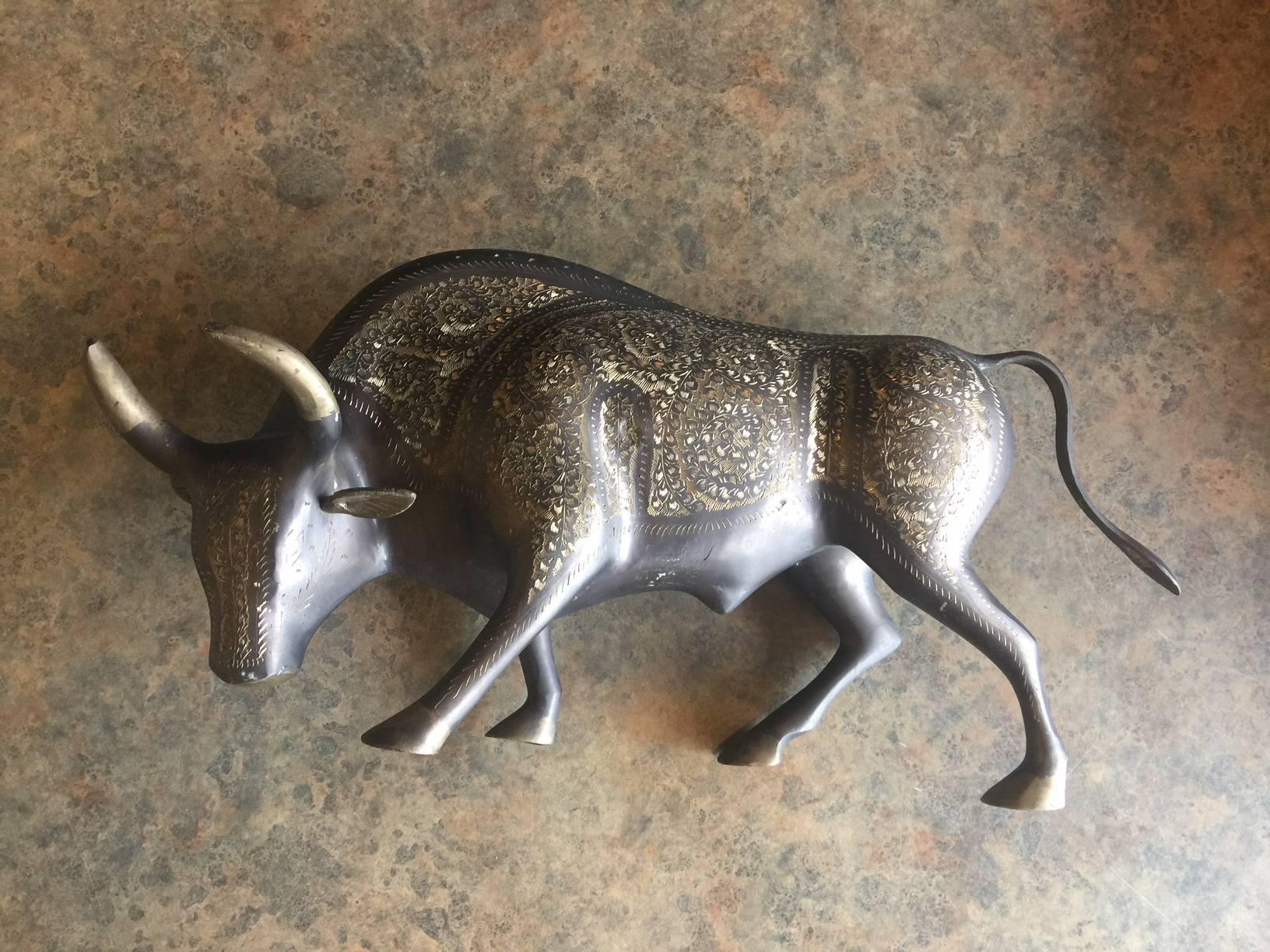 Impressive midcentury brass sculpture of a charging bull, circa 1970s. The piece is heavy with a nice vintage patina and is decoratively etched in a ornate Spanish pattern which brings depth to the piece.
