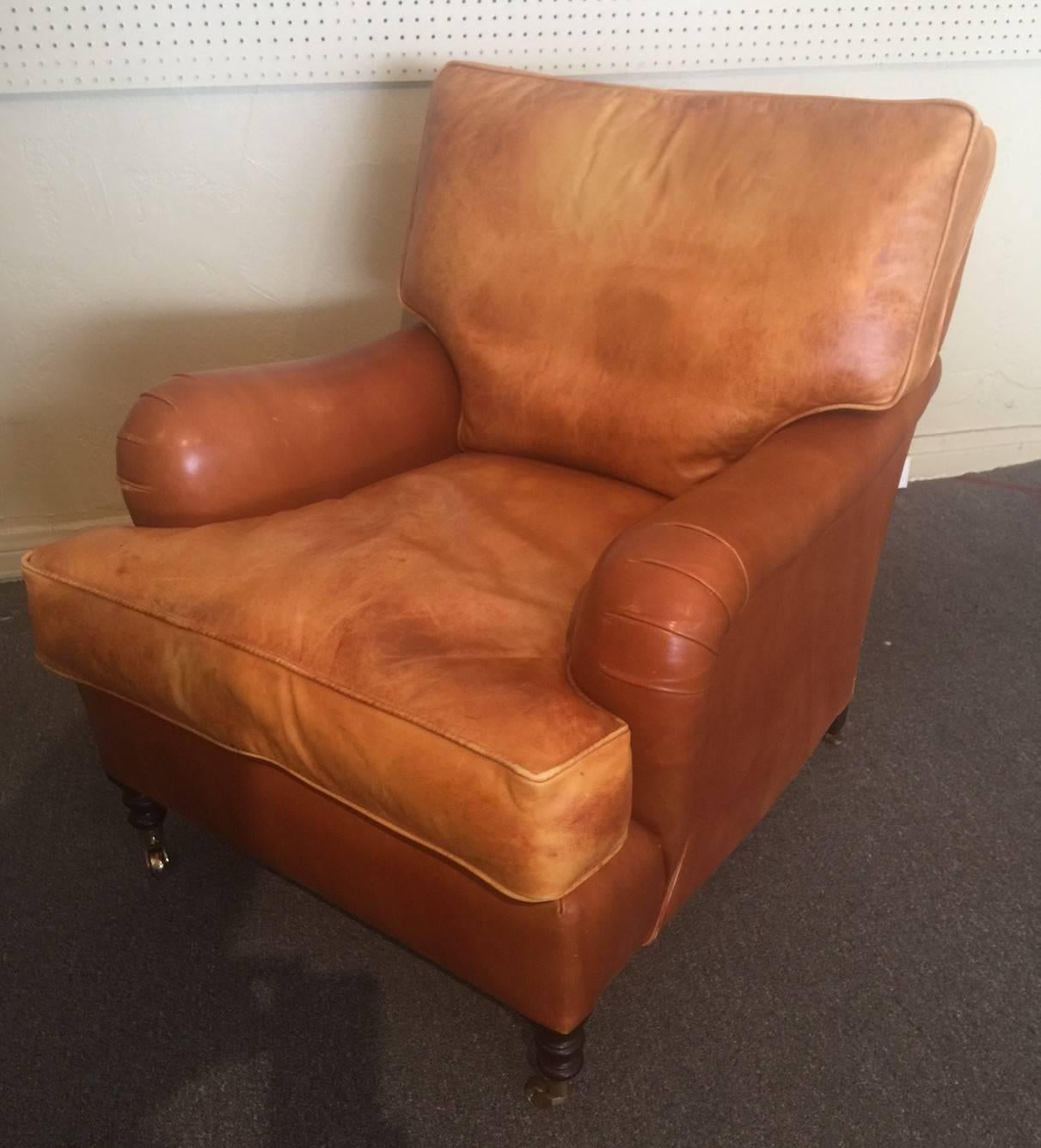 A classic pair of distressed leather club chairs by renowned English furniture maker George Smith. The chairs feature solid wood turned legs with brass casters. Great traditional look!