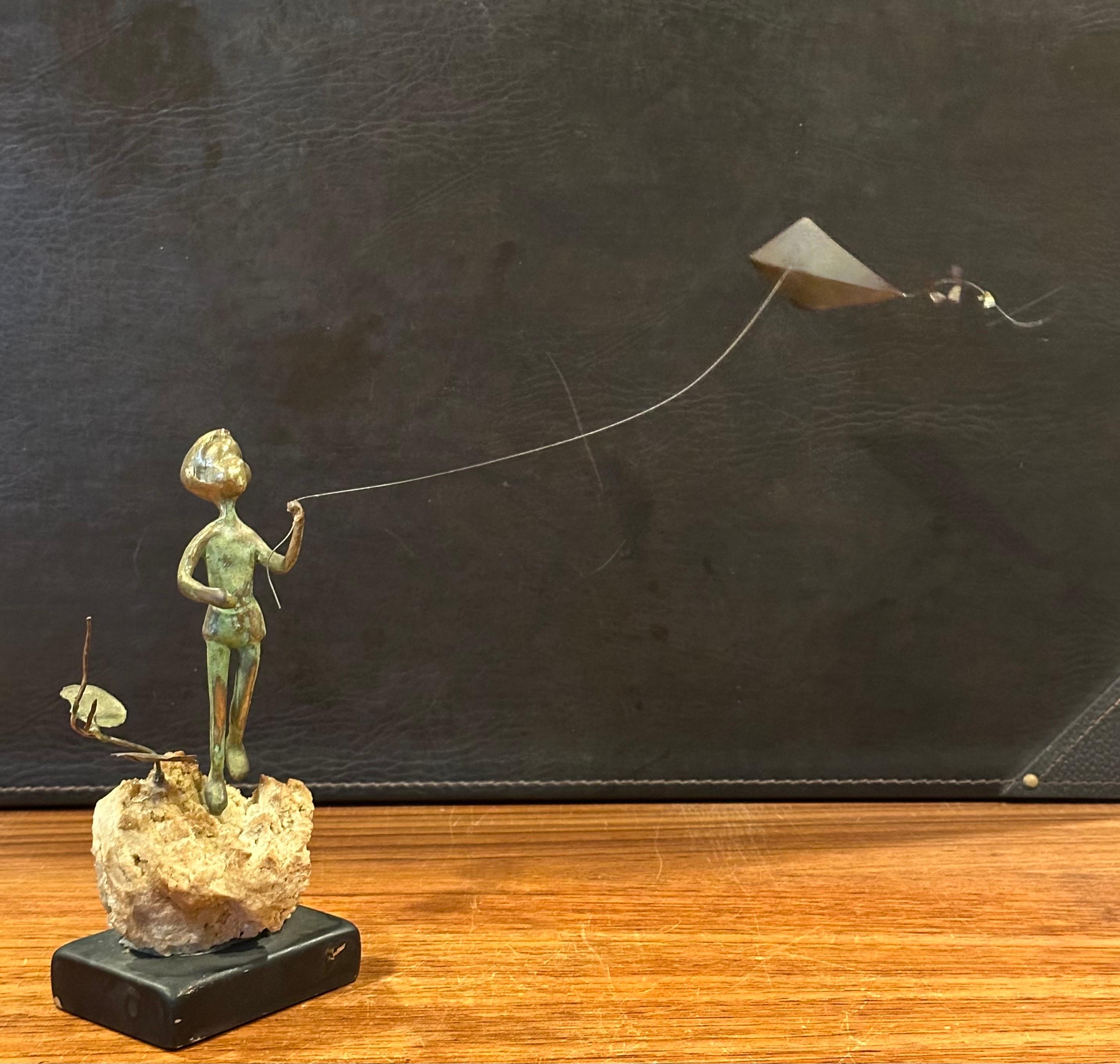 Niño volando una cometa Escultura de bronce sobre roca volcánica de Malcolm Moran Estadounidense en venta