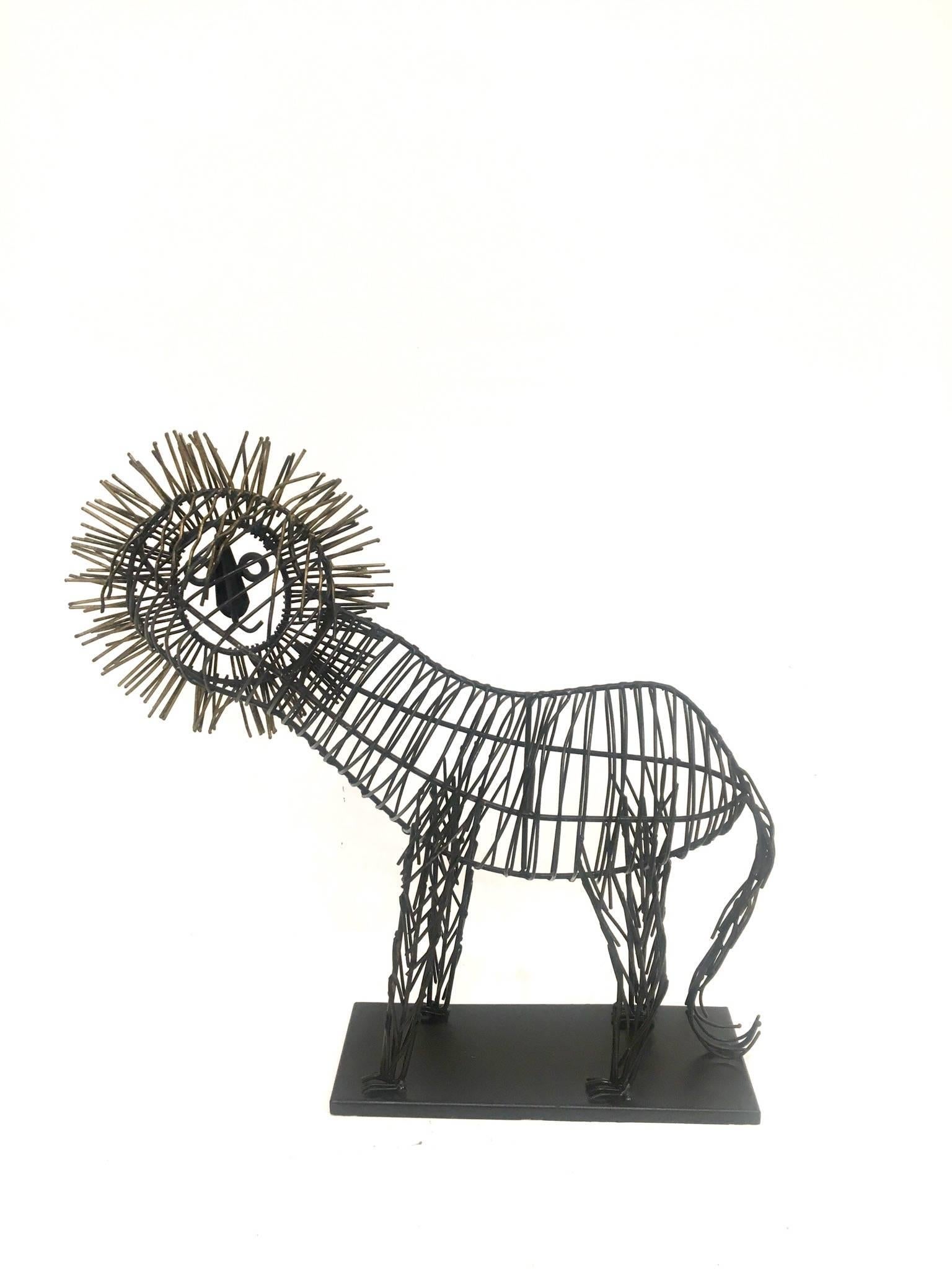 Fun, metal wire sculpture of a male lion sitting on a black metal base. The body is black metal wire and the mane is tinted in gold. The piece is unsigned but in the style of C. Jere, circa 1980s.