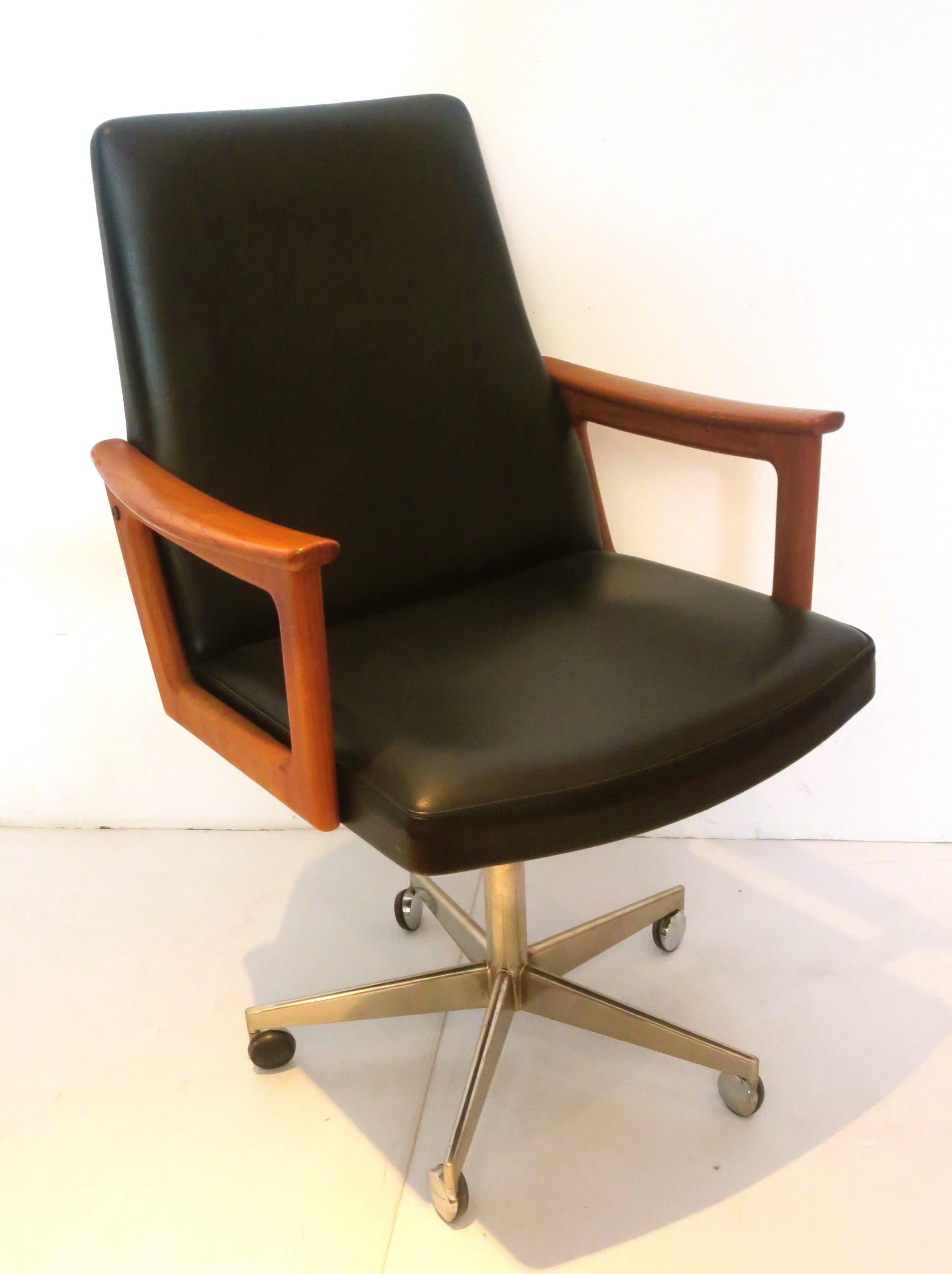 Beautiful single executive arm chair designed by Erik Kirkegaard, circa 1960s solid teak arms, the chair reclines back and forward, also goes up and down, black Naugahyde original material in good condition on a chrome base on casters.