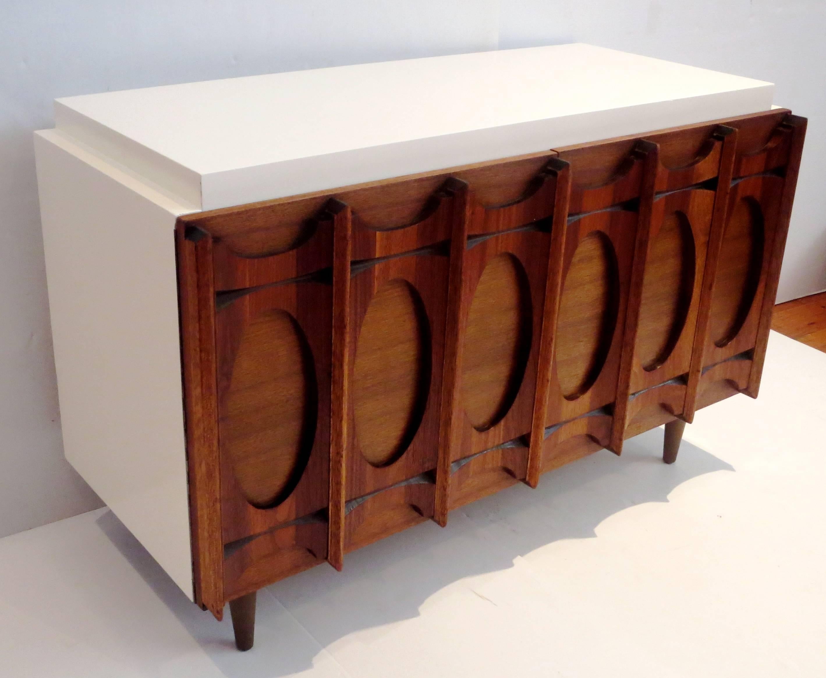 One-of-a-kind small, low cabinet circa 1950s. Beautiful sculpted walnut front doors and a white lacquer body sitting on tapered legs. Great as a mini bar, record cabinet or entertainment console. Item has been completely restored and is in great