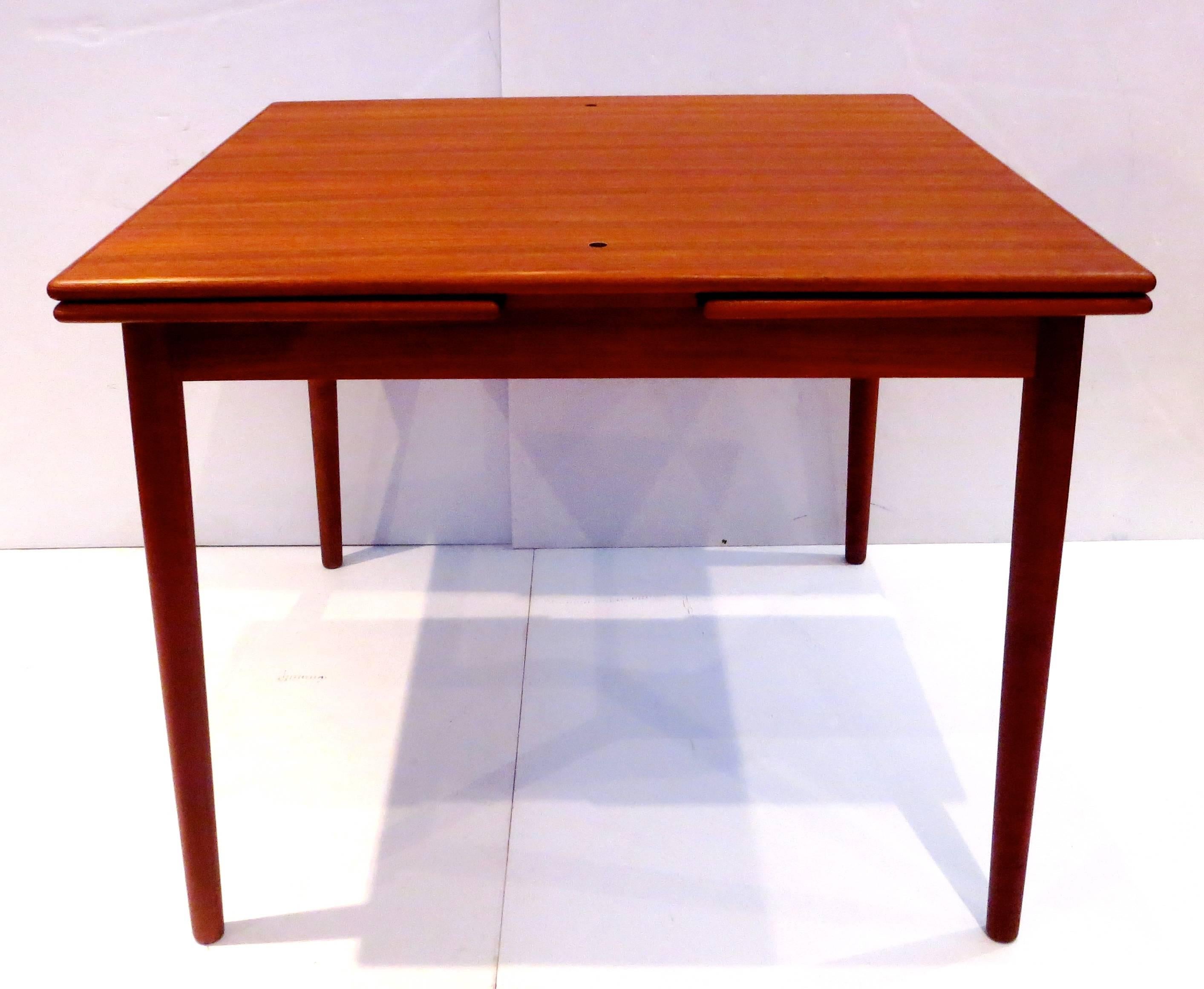 Unique Danish Modern teak table with reversible flip top and two hidden sliding extensions. Excellent design with multi-use. The top flips over and becomes a game table with a black leather surface. Has the original label and comes with the Danish