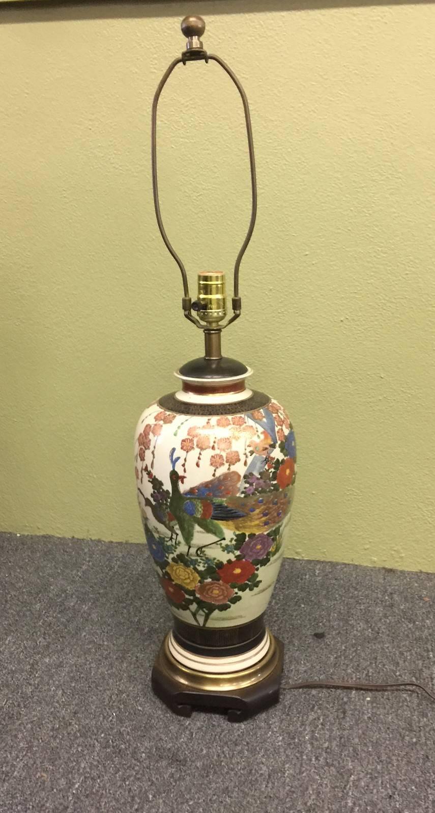 Japanese ginger jar style, hand-painted Satsuma (peacock) table lamp by Frederick Cooper. This stunning lamp sits on a carved wood base and has brass hardware, lid and finial. Wonderful piece!