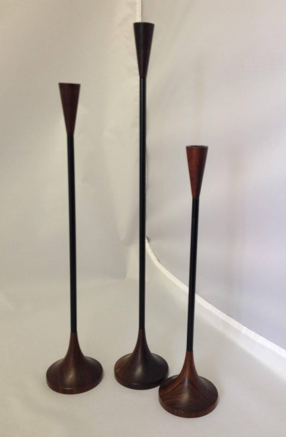 A hard to find set of graduated, Mid-Century candlesticks from craftsman Sam Mann. Turned rosewood base and top with black steel metal shaft. Mann designed products for Copco and was featured in periodicals such as Craft Horizons and Everyday Art