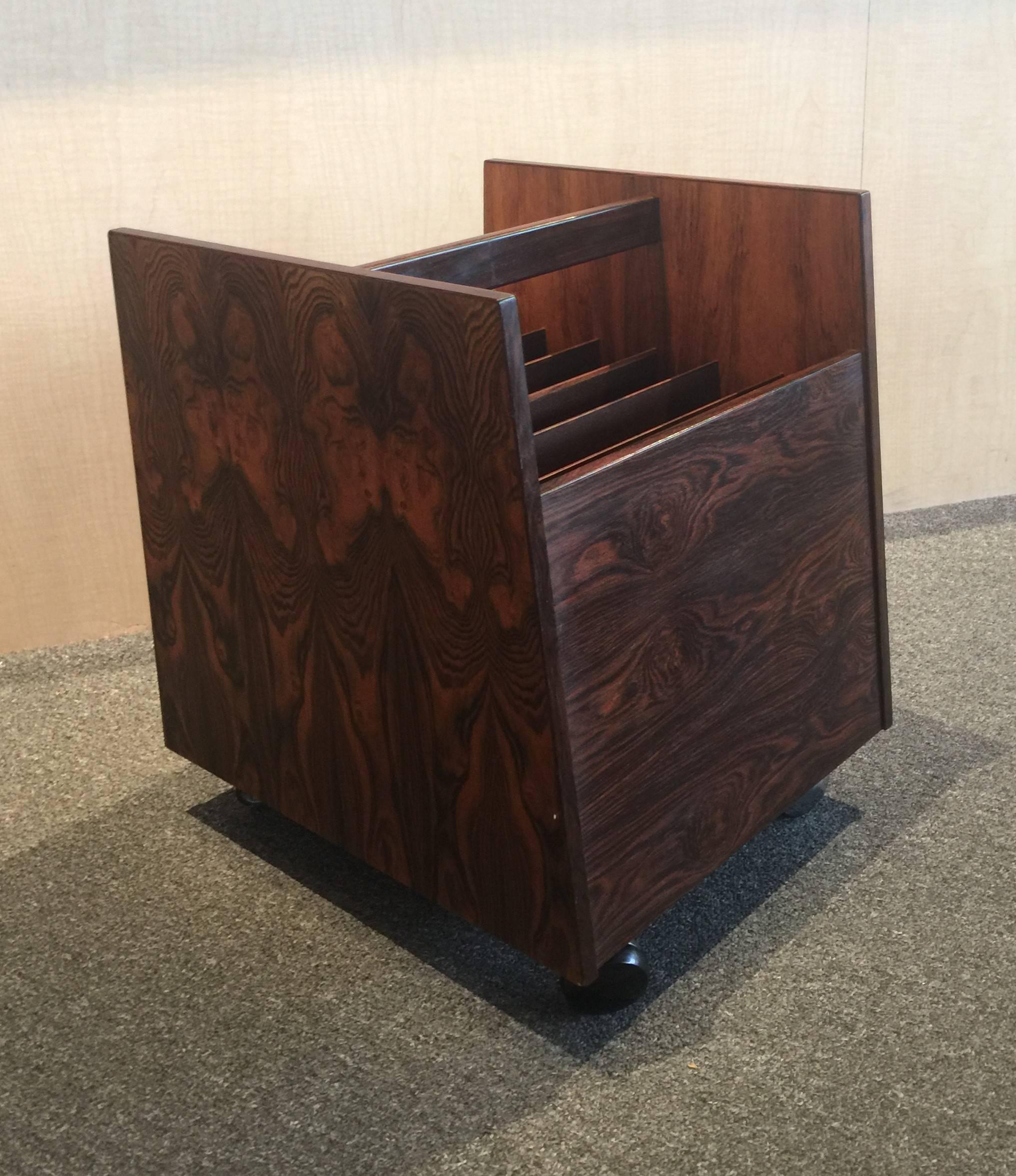 Gorgeous mid-century rosewood record / magazine rack by Rolf Hesland for Bruksbo of Norway, circa 1960s. The piece is in very good vintage condition wiith one minor exception; one of the four black plastic rollers on a caster is missing (see