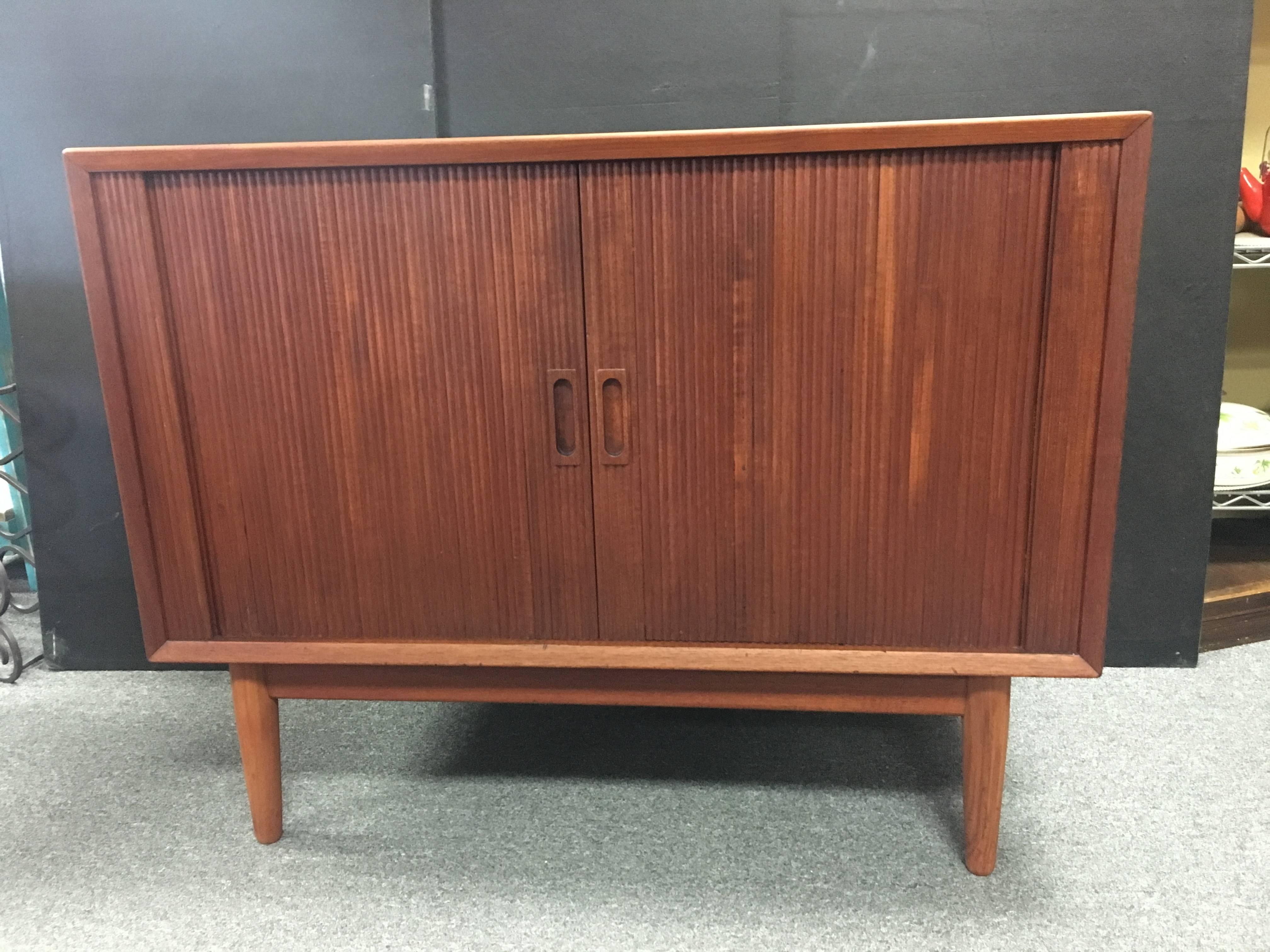 Beautiful and versatile small teak cabinet with tambour doors, a removable inner centre shelf and a finished back. The cabinet has been completely refinished and is in great condition with a couple of small dings. Overall, a wonderful Mid-Century