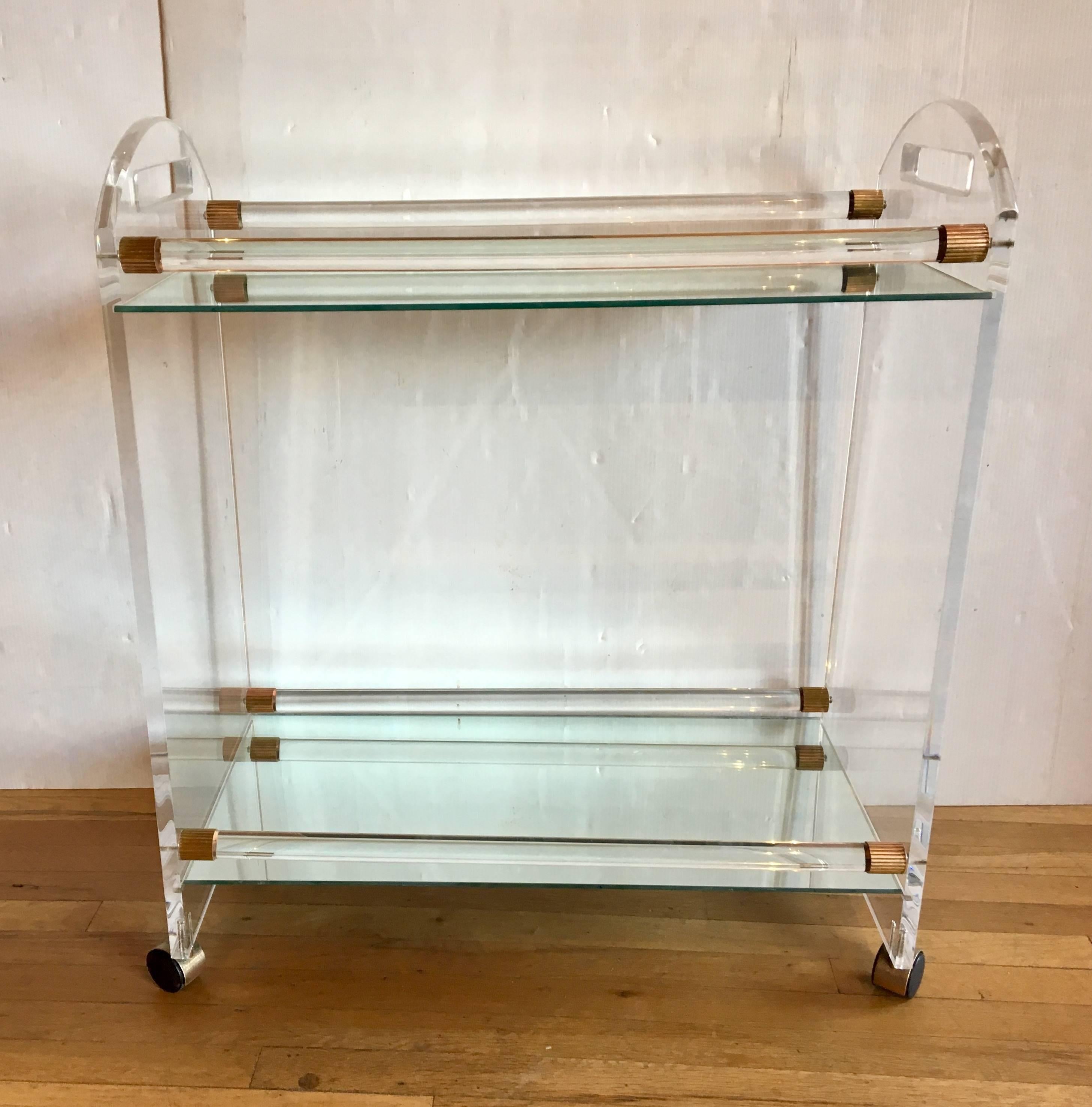 Elegant unique bar cart, circa 1970s, we polished the Lucite and the brass accents and mirrors the casters shows some wear on the top as shown due to age, overall nice clean condition.