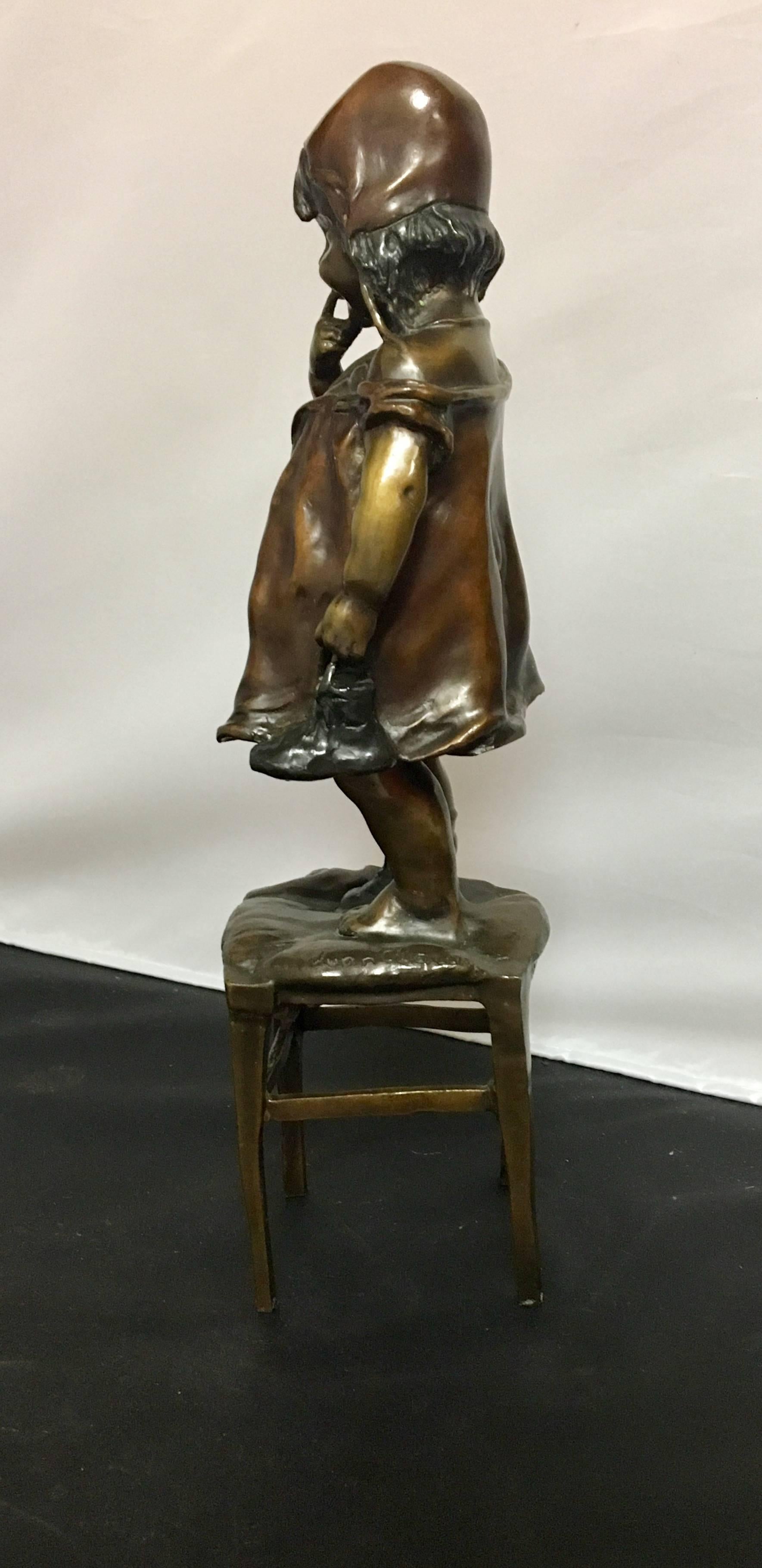 Charming Art Nouveau inspired bronze figurine of a young girl standing on a stool signed by Juan Clara with foundry marks.