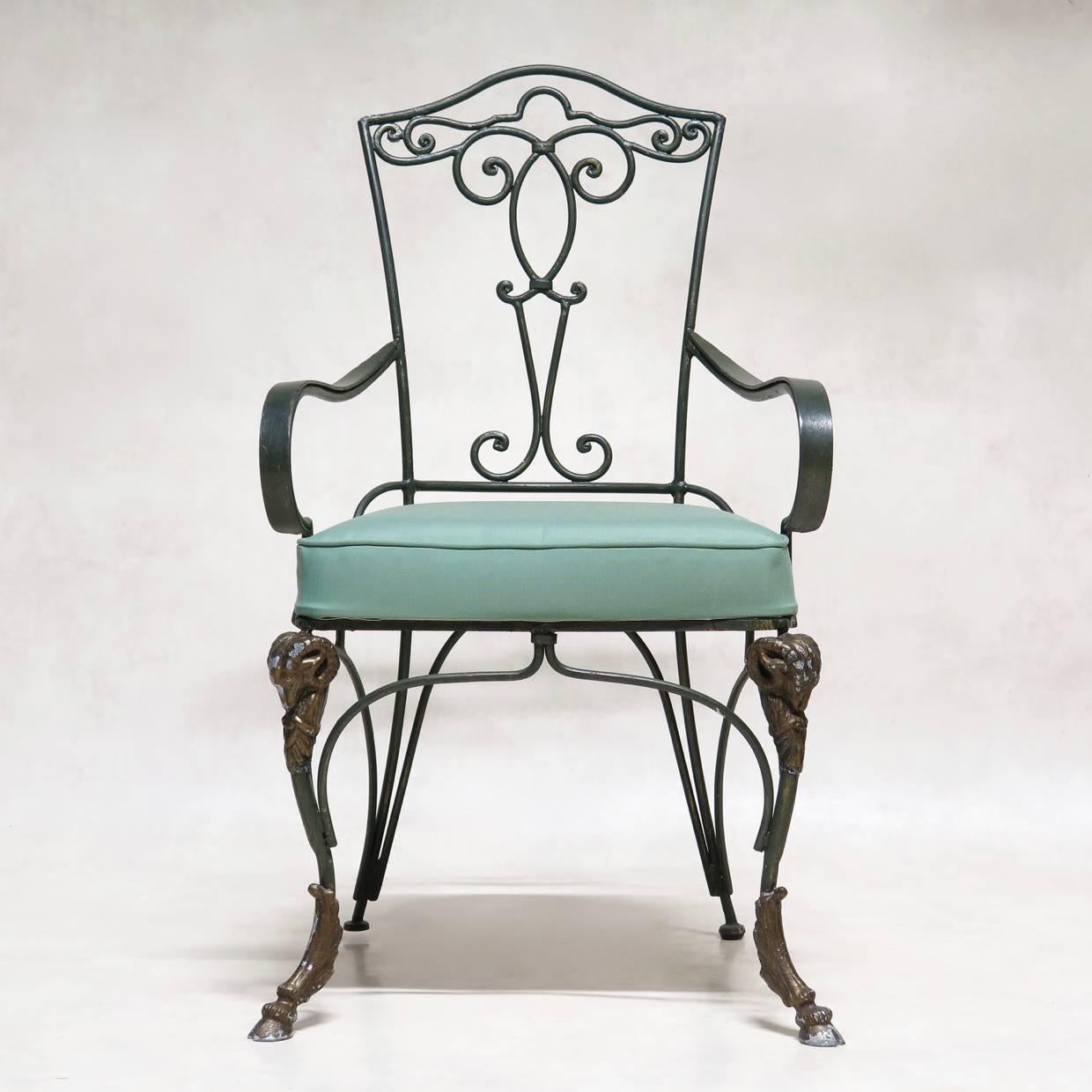 Set of four elegant chairs inspired by the 1940s, painted dark green with bronze highlights. The front legs feature striking rams head detailing on the knees and end in cloven hooves. The back legs extend gracefully outwards. Gently curved armrests.