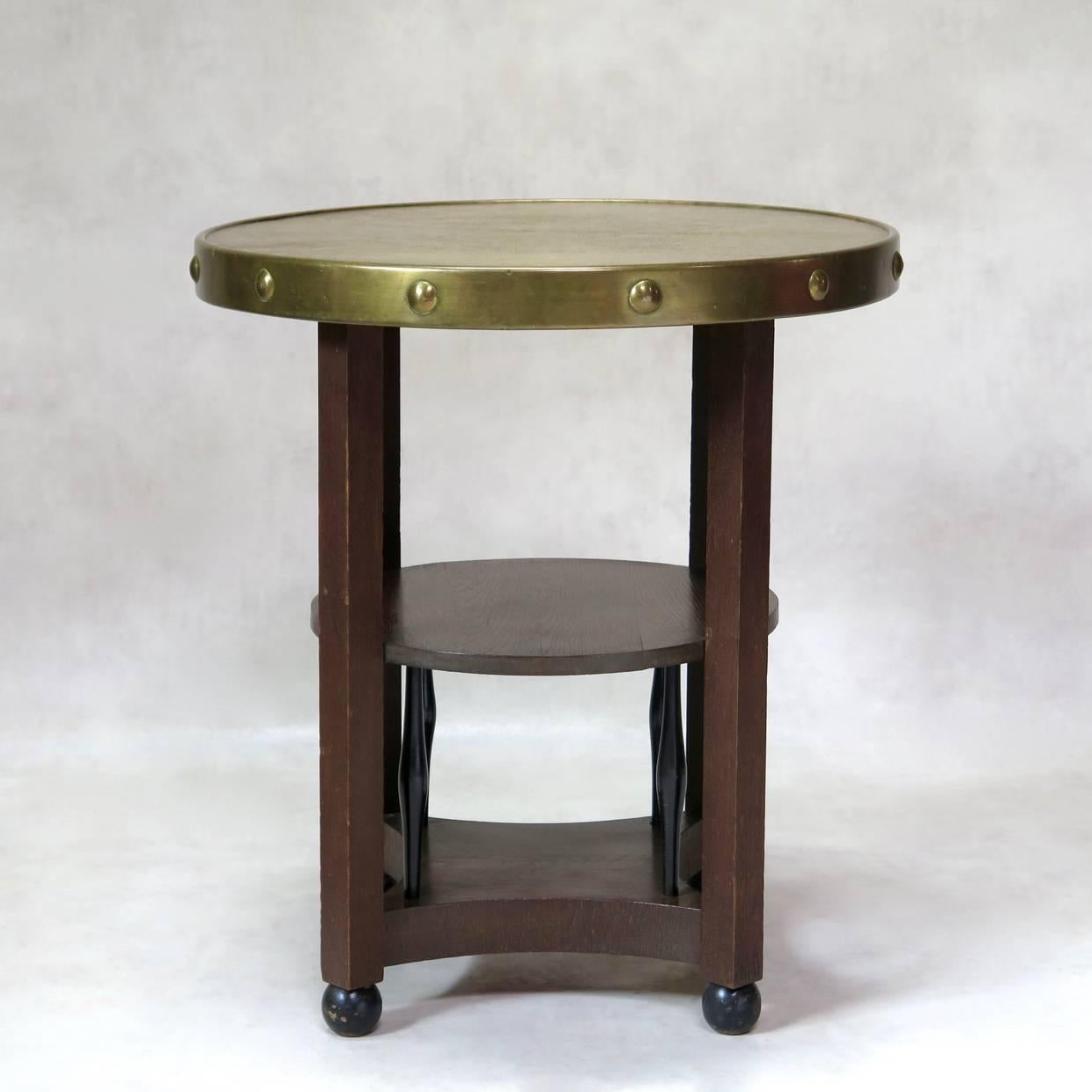 Elegant Secessionist or Arts & Crafts style gueridon with a hammered copper top with nail detailing around the edge. Wooden base with a mid-height shelf, supported by oblong-shaped uprights. These are of contrasting ebonized wood, as are the ball