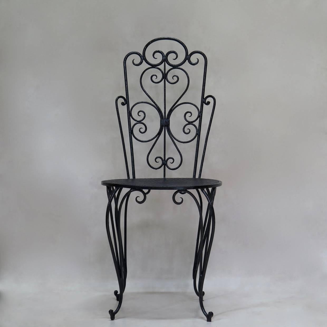 Alluring pair of iron side chairs, with original glossy black paint. Curlicue design on backs. The round seats have a traditional cloverleaf pattern and are raised on cabriole legs, ending in dainty scrolled feet.