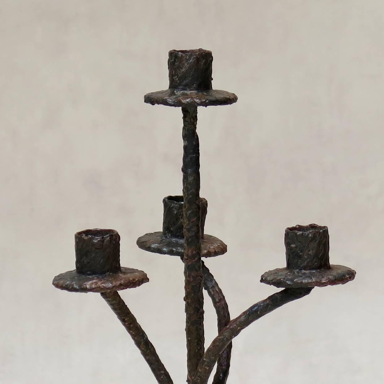 Pair of heavy, textured iron candle holders raised on a helicoid tripod base. Each candelabra holds four candles.