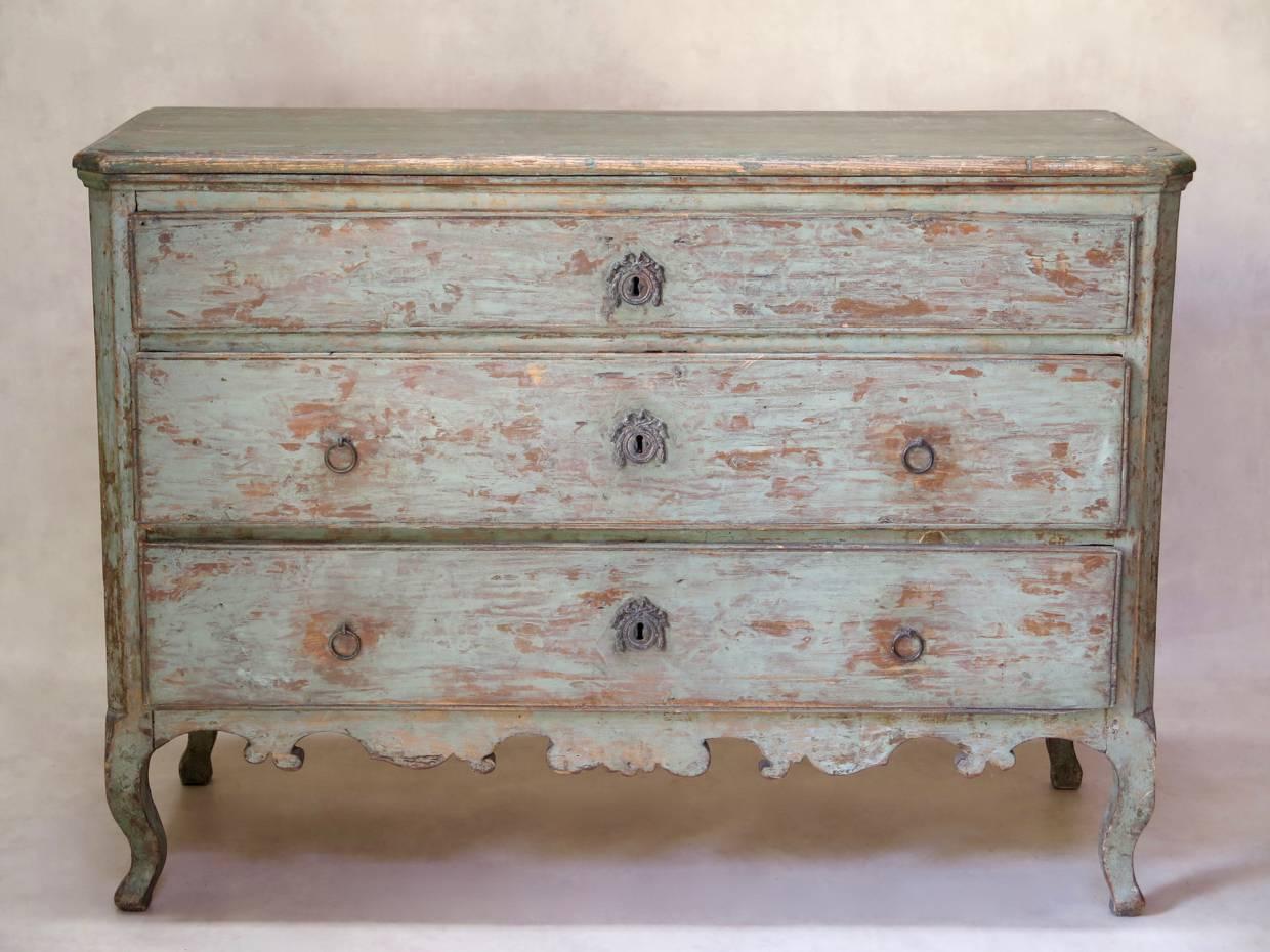 Louis XV style three-door commode with canted corners, raised on cabriole legs. The top is of a slightly darker green than the body. The inside of the drawers have been covered in antique block-painted paper of various patterns.