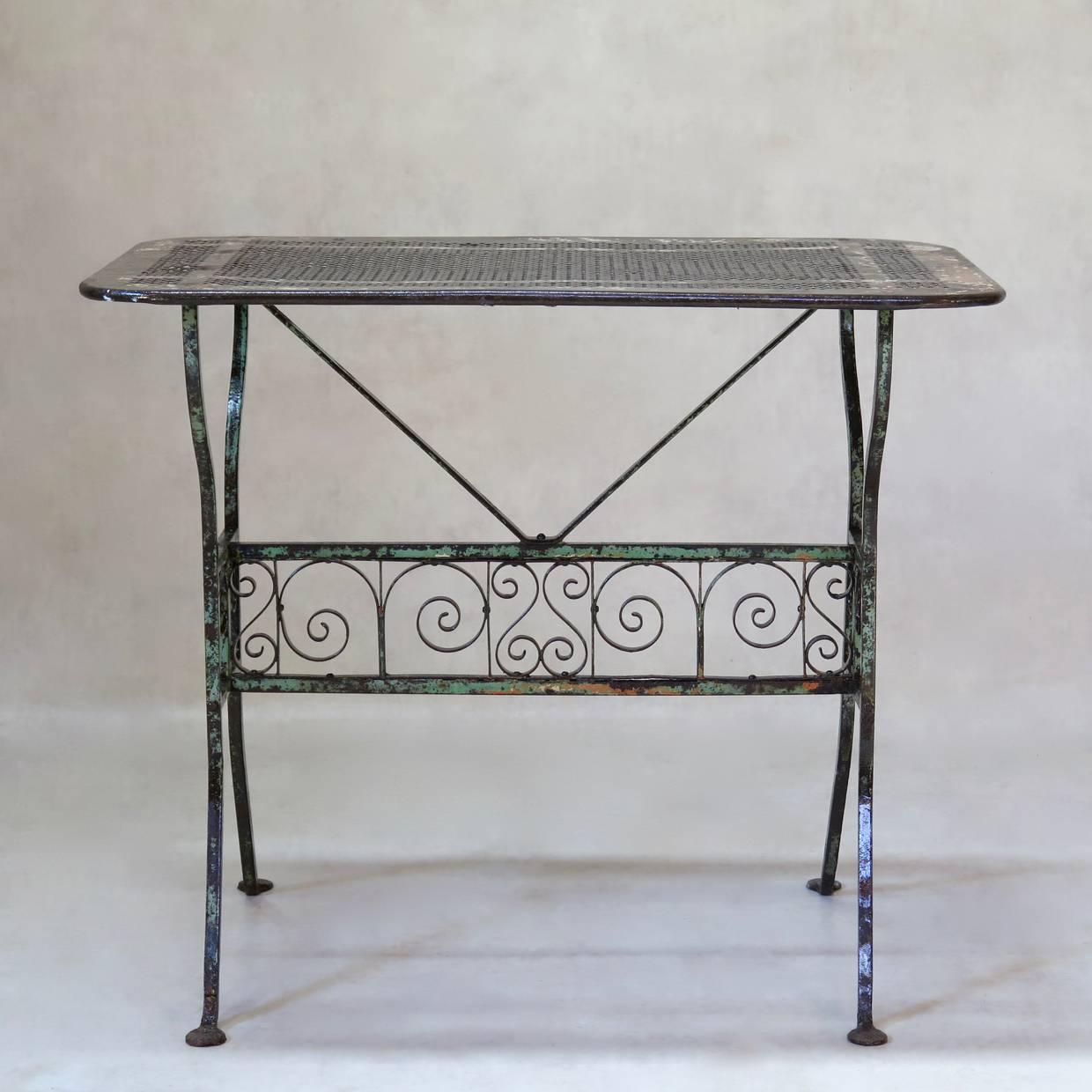 Table en fer forgé inhabituelle et élégante qui a conservé sa peinture orange et verte d'origine. Dessus en tôle à motifs de trèfles.
