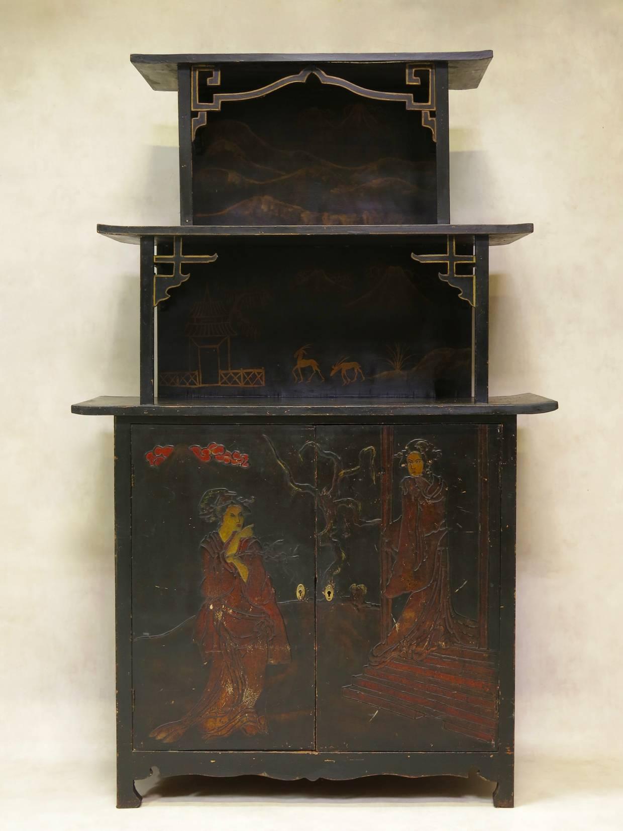 A decorative Chinese style piece of furniture with a closed cabinet section below and a tiered, pagoda-like shelving section above. Ebonized wood, with painted decor in relief.