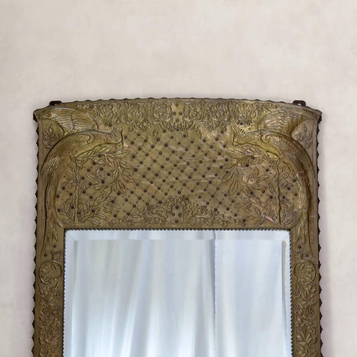 Elegant mirror with an unusual frame of repousse copper decorated with birds and foliage. The frame is signed 