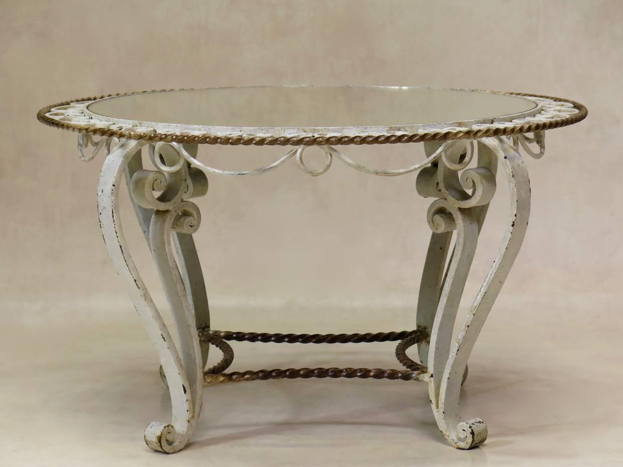 Charming French Art Deco coffee or side table from the 1940s with a heavy yet dainty wrought iron base, with original cream and gold paint. The mirrored top is set in a decorated surround.