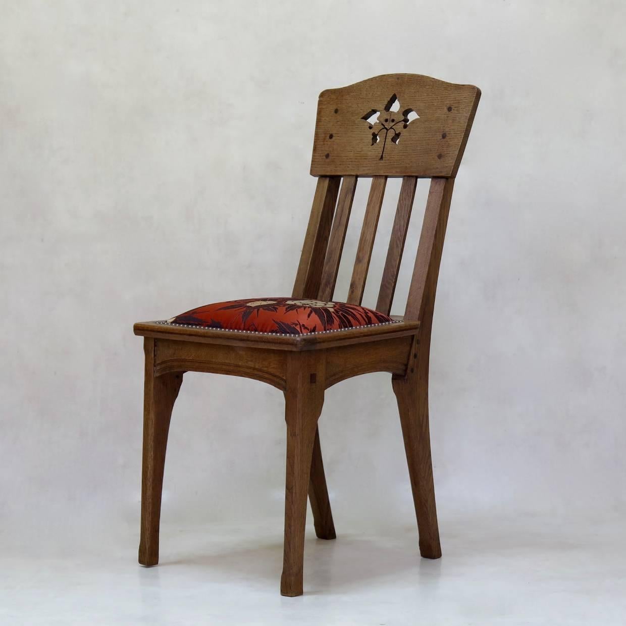 Set of six oak dining chairs by French designer Léon Jallot. Simple lines in the Arts & Crafts taste. Beautifully assembled. Cut-out leaf design on the backs. Seats upholstered in vintage Art Deco fabric.
