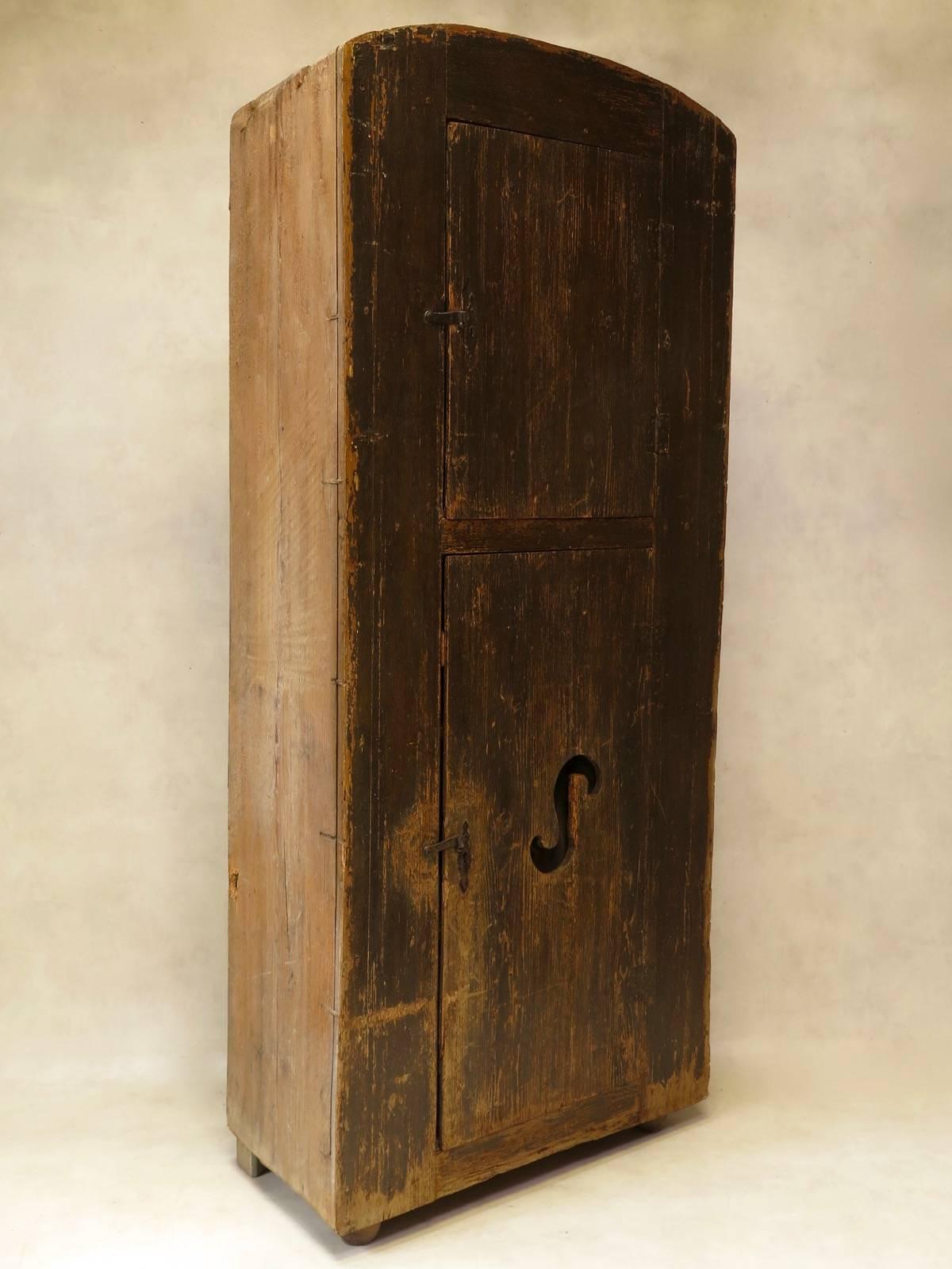 Unusual rustic two-door pinewood cupboard. The façade is painted in a faux-bois finish. Cut-out detail on the lower cupboard door backed in wire mesh. The back and sides are rough-hewn, as it would originally have been encased in a wall, with only