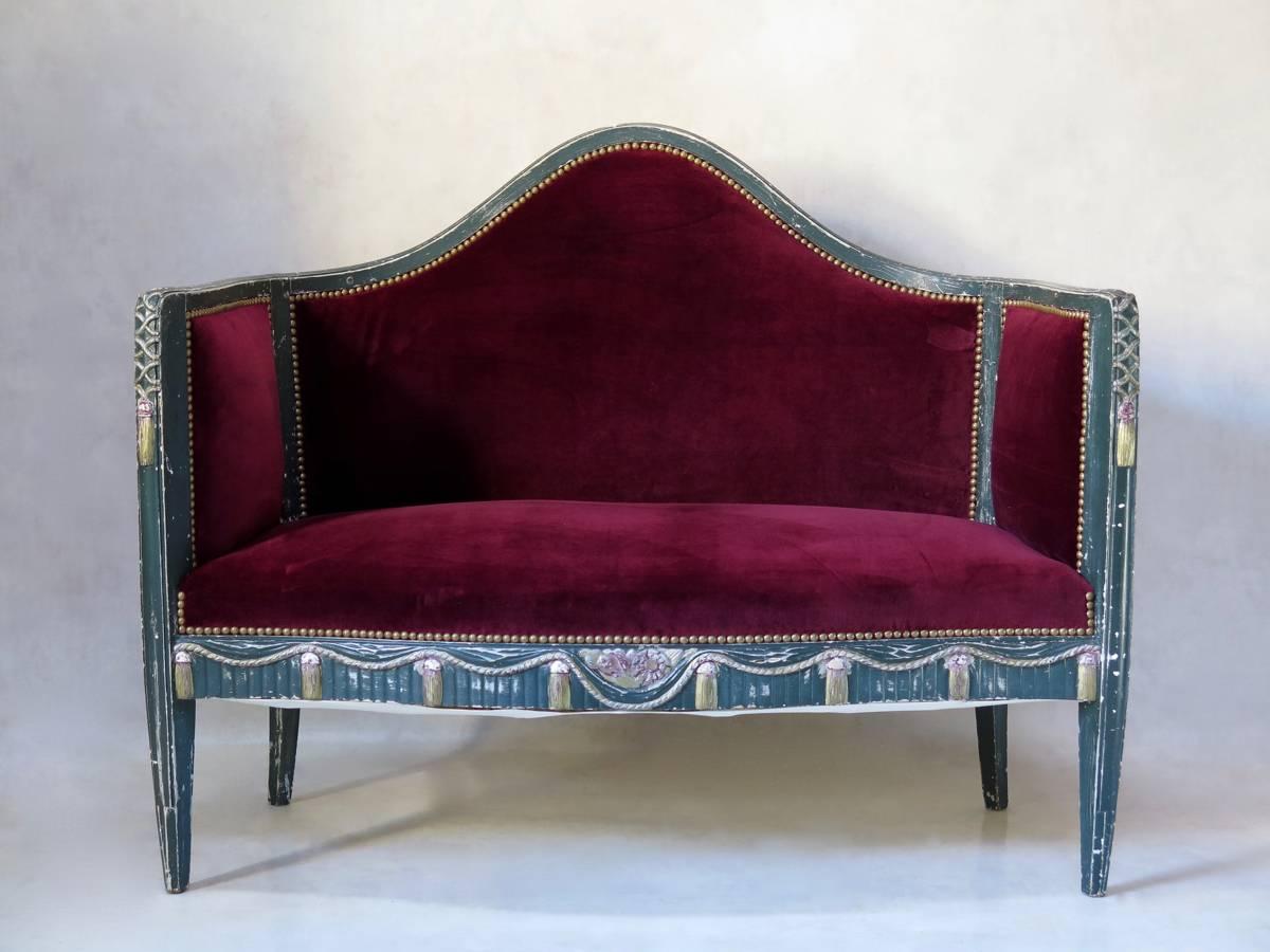 Very pretty Art Deco loveseat or sofa. The wood structure is carved with a rope and tassel decor on a fluted background, and painted in the original green/blue color, with details picked out in gold and pink. Newly upholstered in plush, deep red