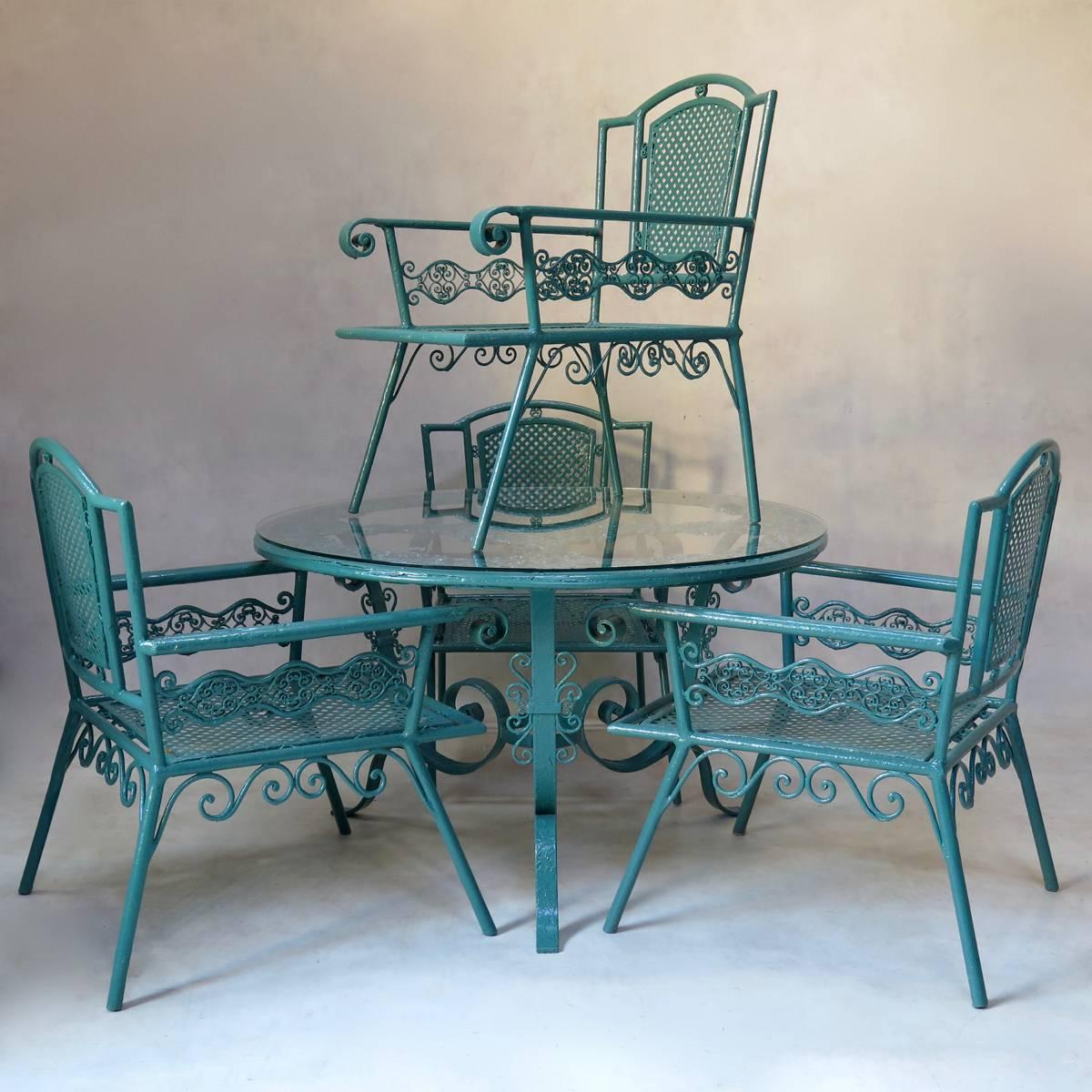 Absolutely gorgeous and one-of-a-kind outdoor iron set comprised of a round coffee table and four low and deep armchairs. Very pretty curlicued ironwork, with latticework in the backs and seats of the armchairs and lace-like ironwork throughout.