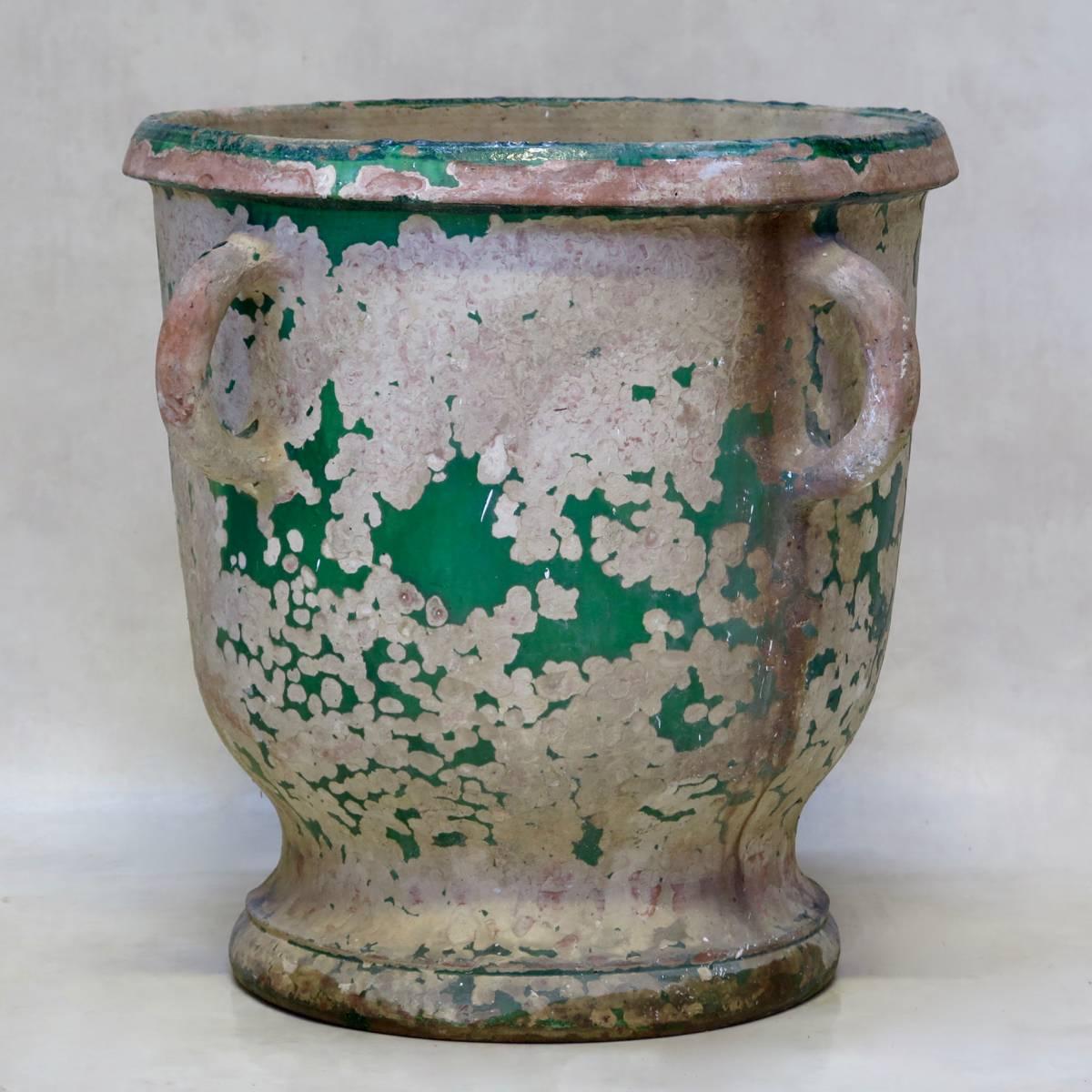 Rare, large planter from Anduze, with four handles around the top. The beautiful deep green glaze has largely worn off. 
A crack runs from the rim down to the base (these planters were not meant to sustain frosts, which caused many of them to