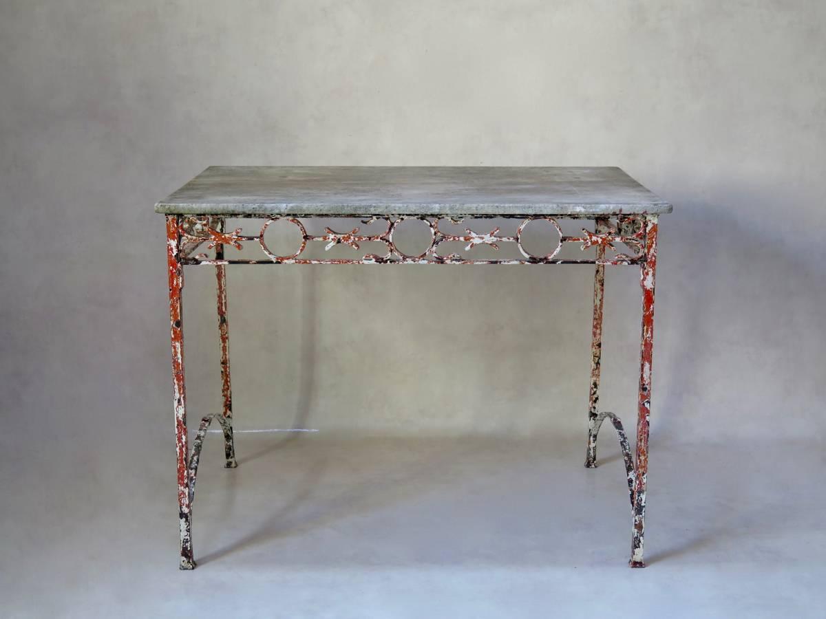 Lovely and unusual console or centre table with a wrought iron base and original marble-top. The decorated apron runs around all four sides of the table. The base retains traces of original white paint, with orange primer visible beneath. The stone