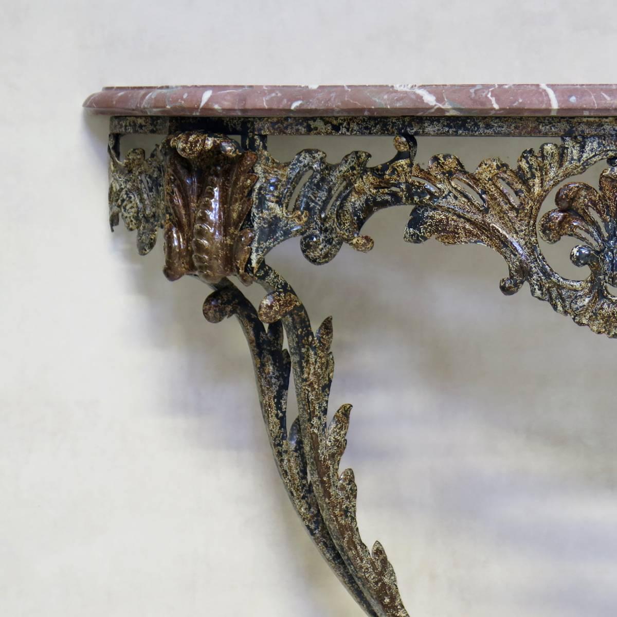 Lovely demilune console table with a forged iron base in the Rocaille style, decorated with acanthus leaves and shell motif. The iron has a gorgeous patina. Original pink marble top.