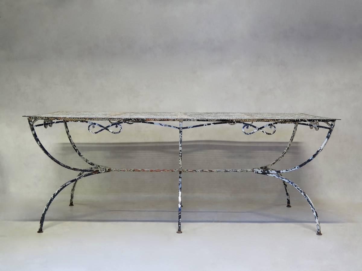 Large wrought iron, bow-motif painted garden or outdoor dining table. The top is made of cloverleaf-patterned sheet metal. Curule-style base, with a bow-motif apron and twisted iron stretcher.
Nice quality. Rare piece.