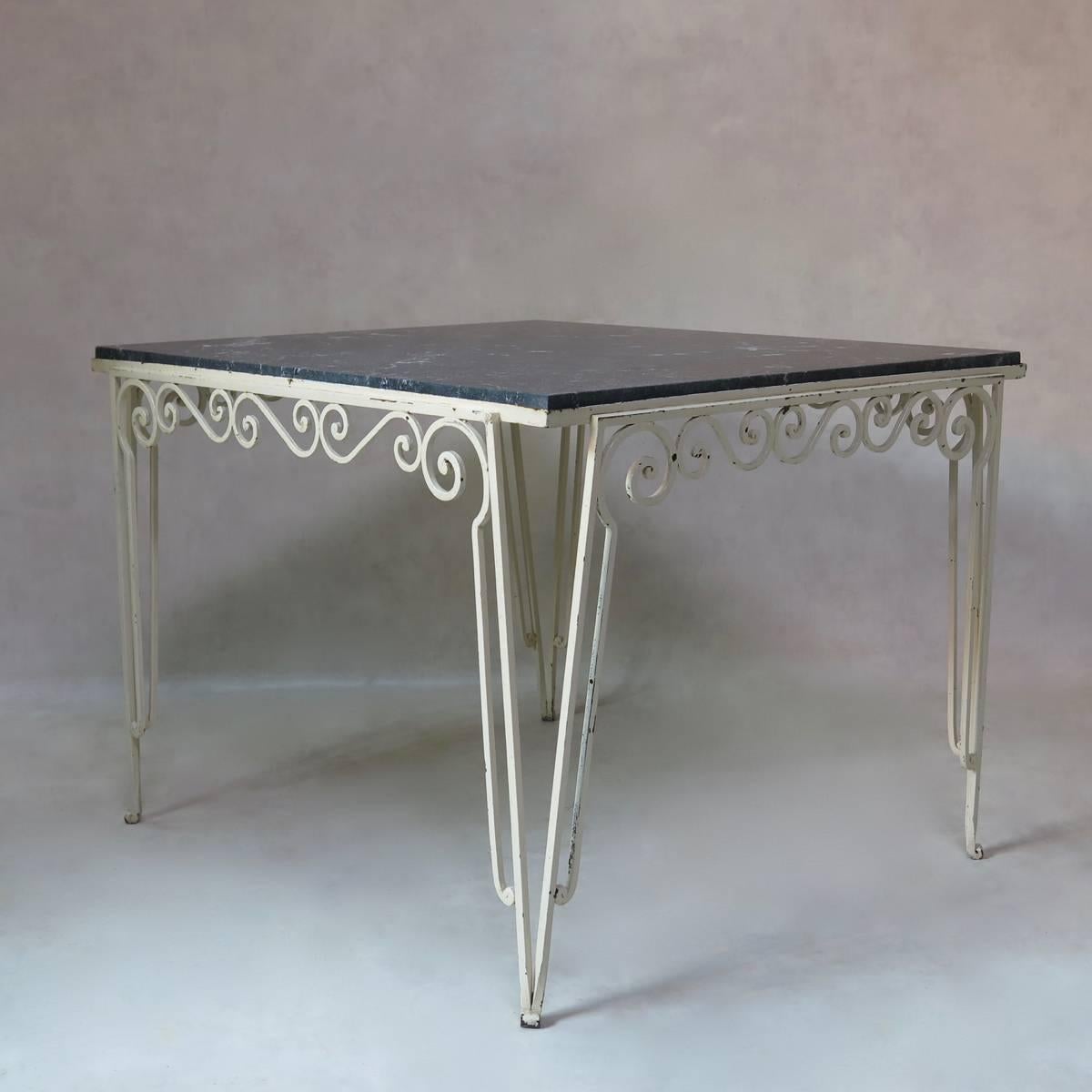 An unusual, large and almost square table with a painted wrought iron base and a mottled black and white stone top.