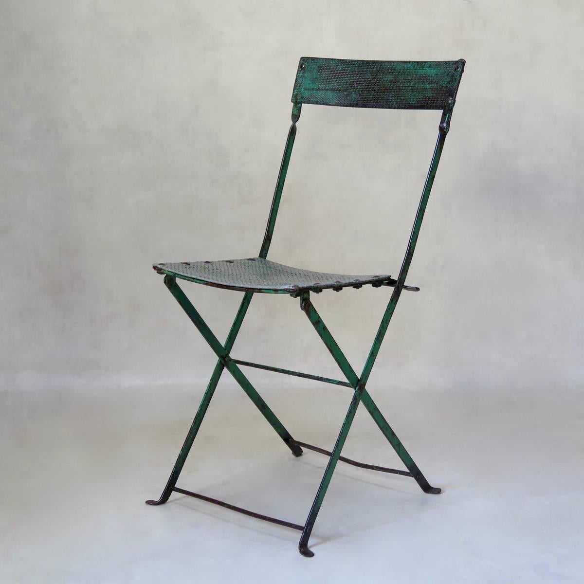 Très belle chaise pliante en fer avec une magnifique patine verte. L'assise et le dossier sont réalisés en tôle d'aluminium perforée.