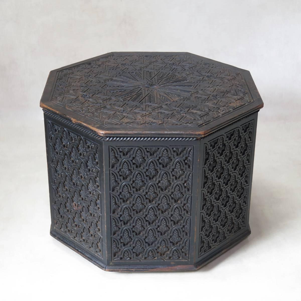 Rare and beautiful octagonal, ebonized wood coffee table with an intricately carved pattern on the sides and top. Mounted on casters.