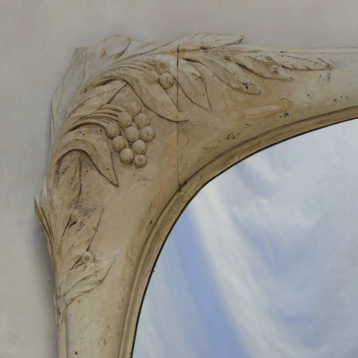 Large and elegant Art Nouveau mirror. The frame is carved with leaves and fruit, and has a white-washed finish.