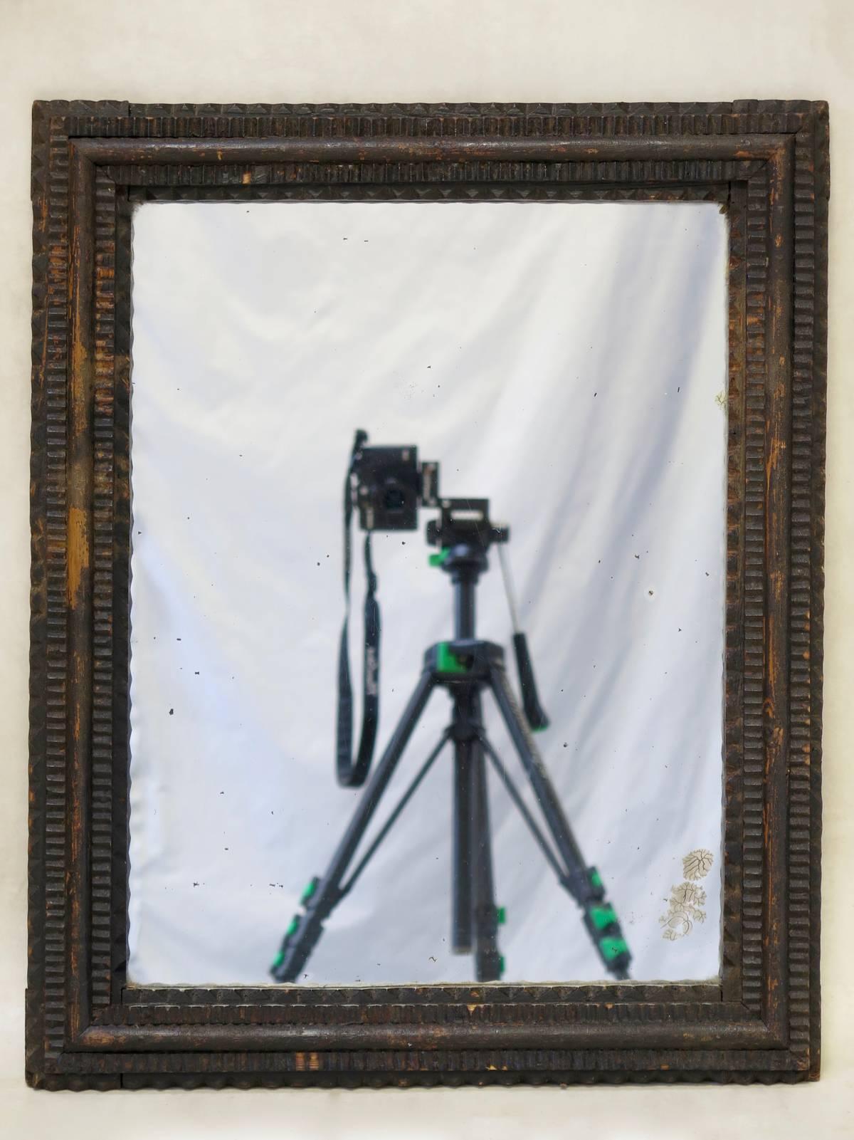 Elegant and minimalistic pair of tramp art ebonized wood frames with antique glass mirrors.