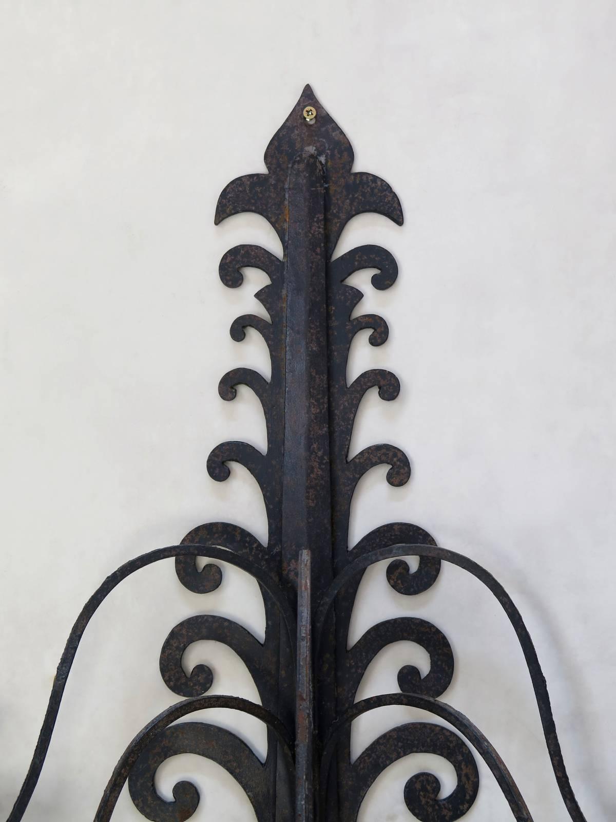 Very lovely set of seven iron sconces. Intricate cut-out design and rivet-decor. Each sconce has seven arms. Originally for use with candles, but could be wired.